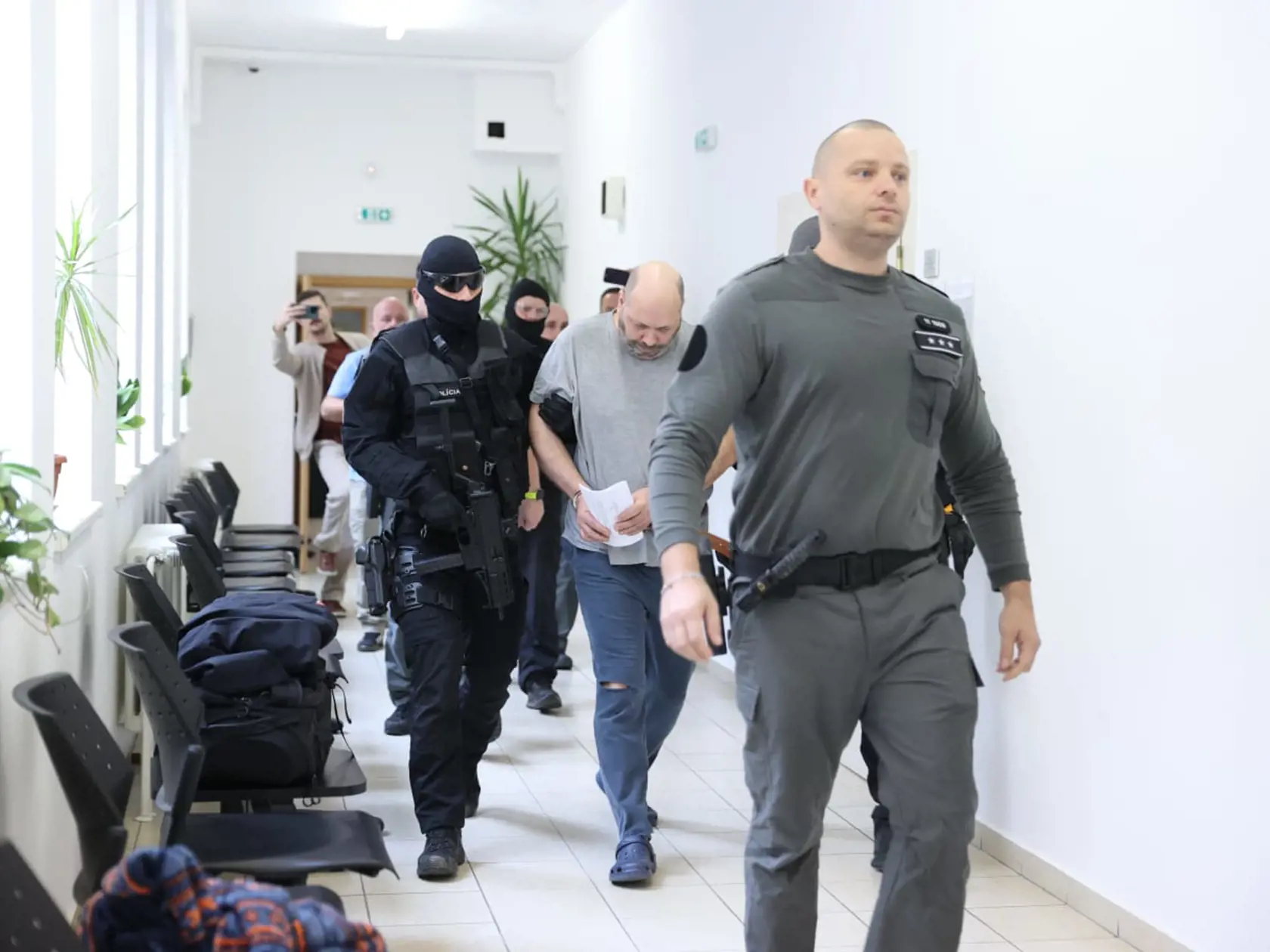 Tomáša (44), obvineného z vraždy svojich rodičov, privádzajú kukláči priviedli na súd 18. októbra 2024.