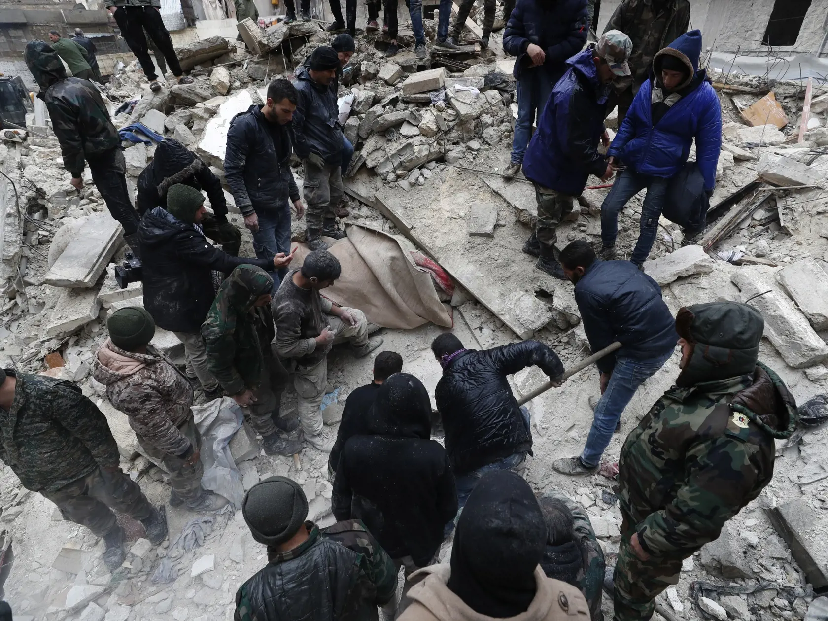 KK25 Aleppo - Pracovníci sýrskej civilnej obrany a členovia bezpečnostných síl prehľadávajú ruiny zrútených budov v sýrskom meste Aleppo 6. februára 2023.