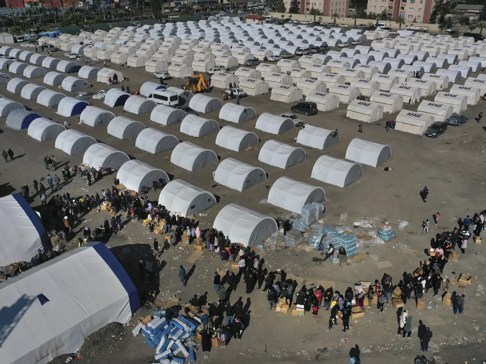 WA 34 Iskenderun - Ľudia, ktorí prišli o strechu nad hlavou pri minulotýždňovom ničivom zemetrasení v Turecku a Sýrii, čakajú v rade na humanitárnu pomoc v stanovom tábore v juhotureckom meste Iskenderun v utorok 14. februára 2023.