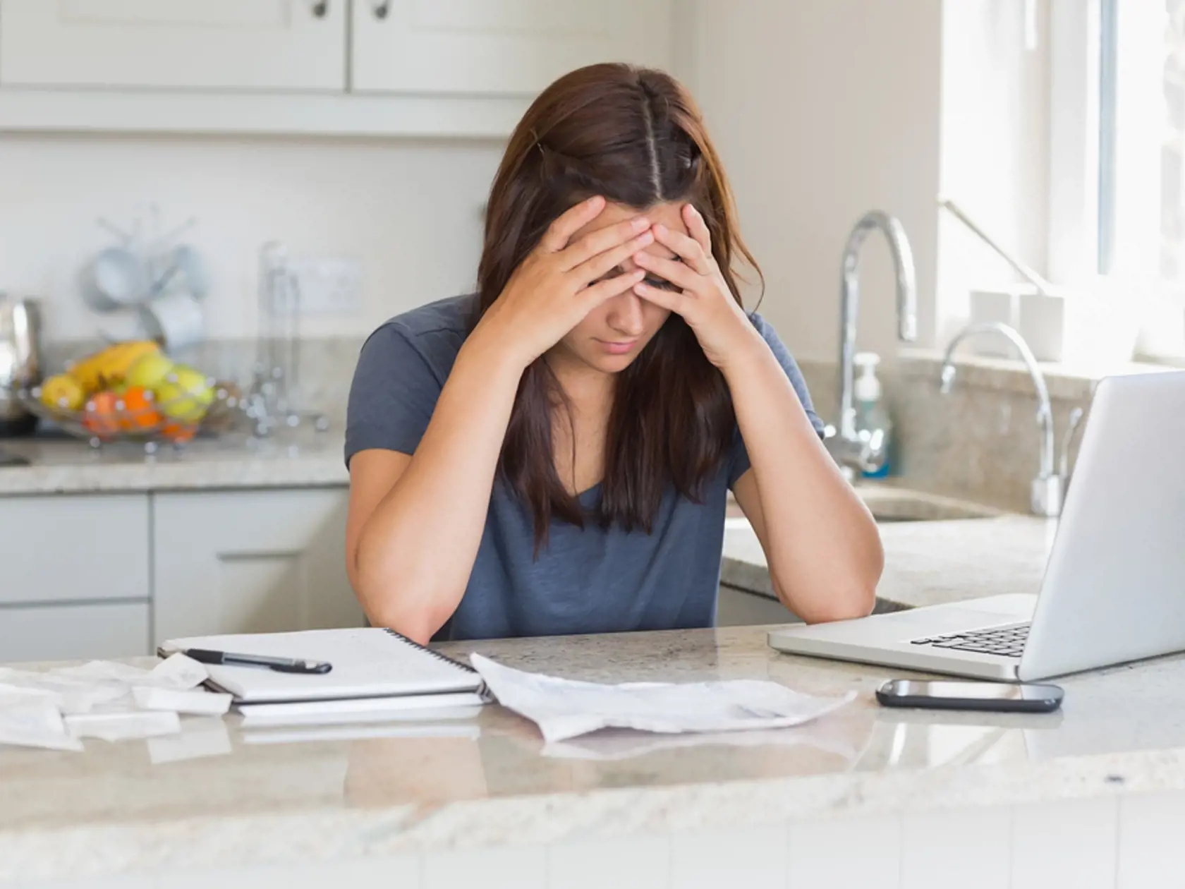 Stressed,Woman,Looking,Down,At,Bills,In,Kitchen