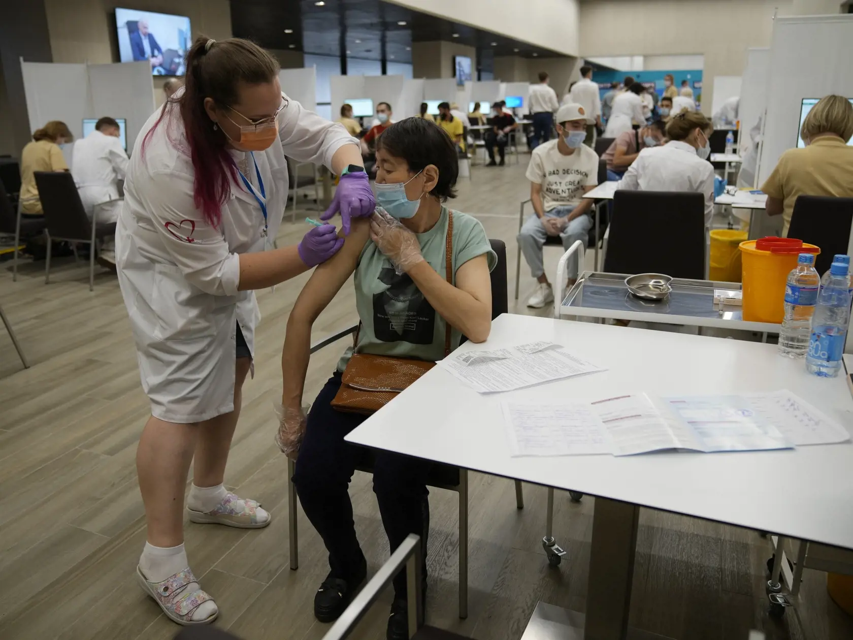JB 56 Moskva - Zdravotníčka podáva ruskú vakcínu Sputnik V zahraničnej pracovníčke pracujúcej v Rusku počas očkovania proti ochoreniu COVID-19 vo vakcinačnom centre v priestoroch Olympijského komplexu Lužniki v Moskve 8. júla 2021. Situácia ohľadom šírenia nového koronavírusu v Moskve sa počas posledných dní postupne stabilizuje. Informoval o tom vo štvrtok starosta ruskej metropoly Sergej Sobianin, ktorého citovala agentúra TASS. Moskovský starosta nedávno informoval, že variantom delta, ktorý 
