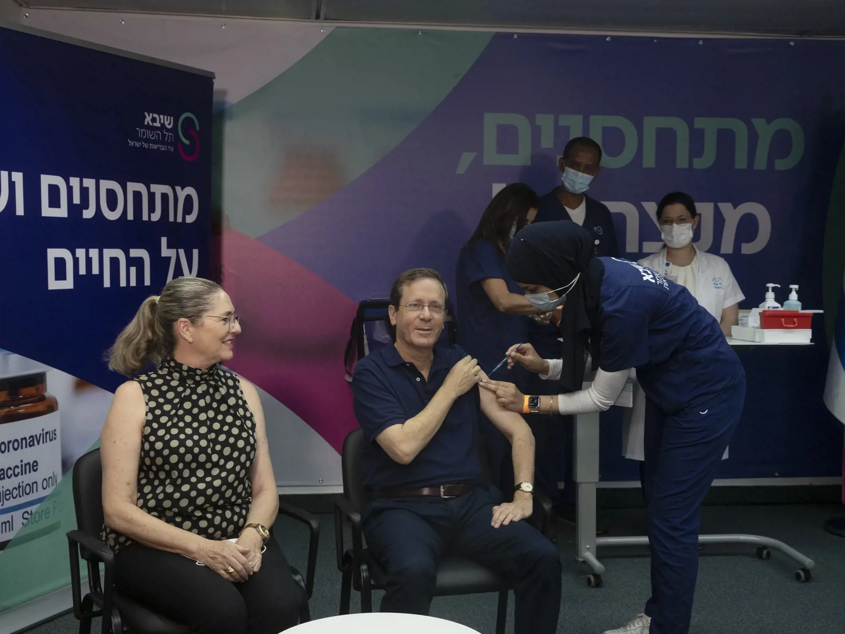JB 66 Ramat Gan - Izraelský prezident Jicchak Herzog (uprostred vpravo) dostáva tretiu dávku vakcíny proti koronavírusu počas vakcinácie v zdravotnom stredisku Sheba v izraelskom meste Ramat Gan 30. júla 2021. Vľavo sedí jeho manželka Michala. FOTO TASR/AP

Israeli President Isaac Herzog receives a third coronavirus vaccine injection while his wife, Michal, left, reacts, at the Sheba Medical Center in Ramat Gan, Israel, Friday, July 30, 2021. (AP Photo/Maya Alleruzzo, Pool)