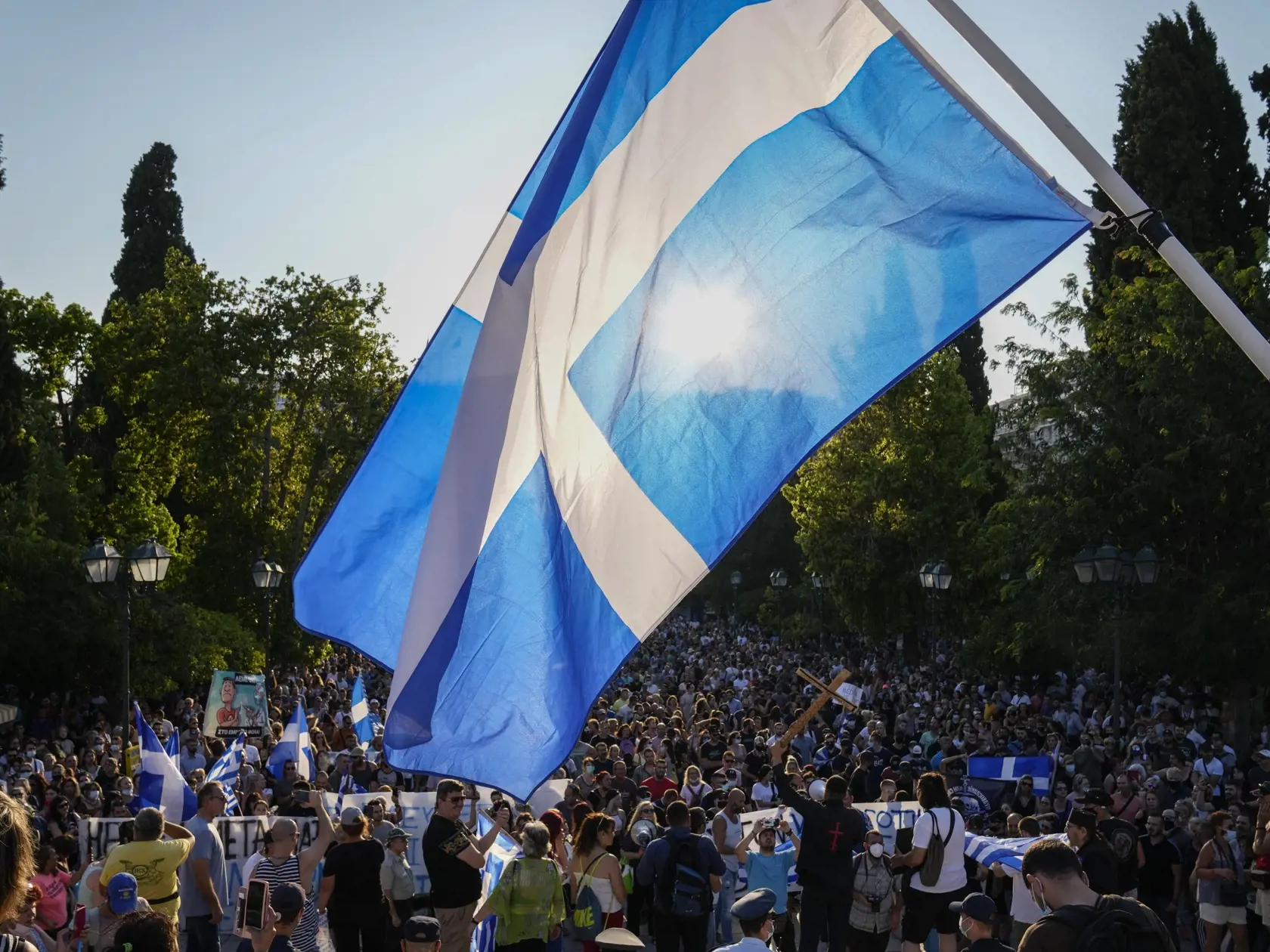 WA 14 Atény - Odporca očkovania drží grécku vlajku počas protestu v centre Atén v stredu 14. júla 2021. Tisícky ľudí protestovalo v stredu podvečer v gréckej metropole Atény a v ´dalších gréckych mestách proti novému balíku protiepidemických opatrení, ktoré vytvárajú na obyvateľov tlak, aby sa dali zaočkovať, informovala vo štvrtok agentúra AFP. Podľa štátnych médií išlo o doteraz najväčšie protesty odporcov vakcinácie v Grécku. Po uvoľnení opatrení v krajine v priebehu posledných desiatich dní 