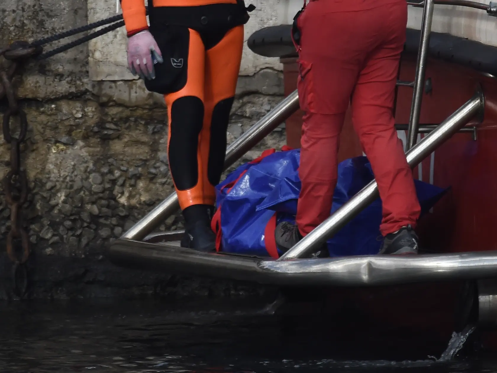 Talianski potápači vynášajú telo jednej z obetí potopenej plachetnice Bayesan.