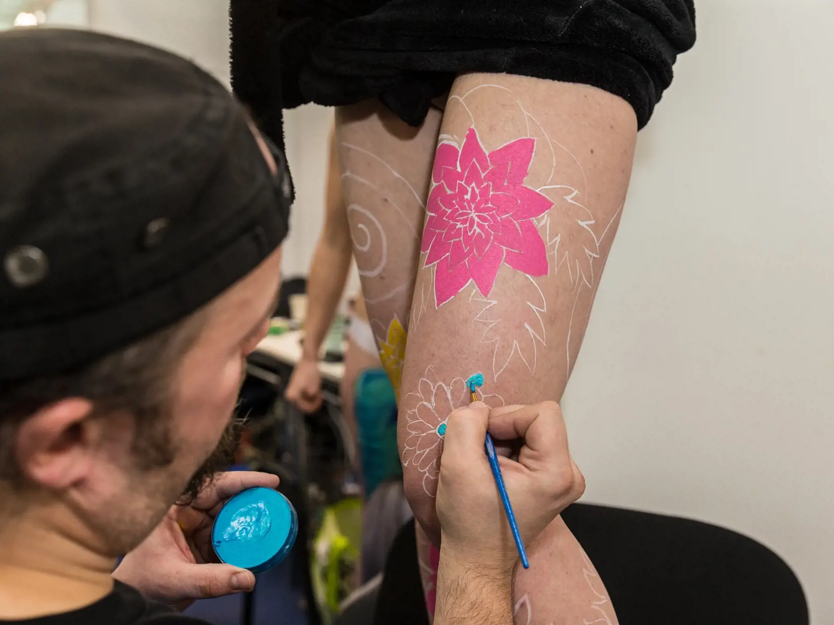 Bodypainter na Interbeauty v Inchebe maľuje detaily na stehno modelky.