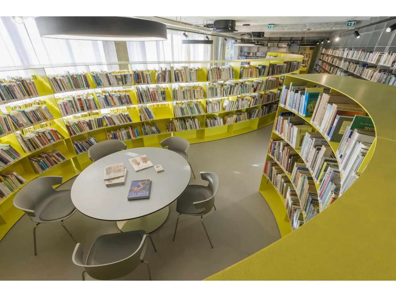 ODDELENIE ODBORNEJ LITERATÚRY MESTSKEJ KNIŽNICE V SENCI: Keďže v priestore s plochou 150 m2 bolo treba uskladniť 15 000 zväzkov, hlavnou výzvou projektu bolo vymyslieť riešenie, ktoré nezaplní celý priestor regálmi. V rámci knižnice by totiž mala byť tichá študovňa, priestor na prácu s počítačom a otvorený priestor, kde je možné usporiadať menšie podujatia (do 30 ľudí). Základným prvkom interiéru je zaoblený regál, ktorý svojím tvarom rozčleňuje vyššie spomenuté zóny.