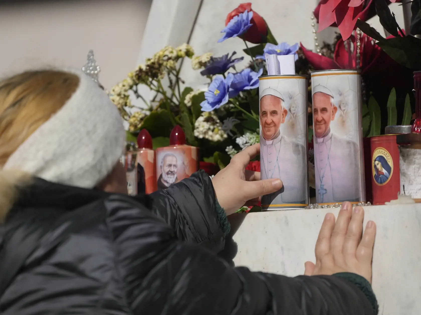 Pred nemocnicou sa veriaci modlia a stále zapaľujú sviečky.