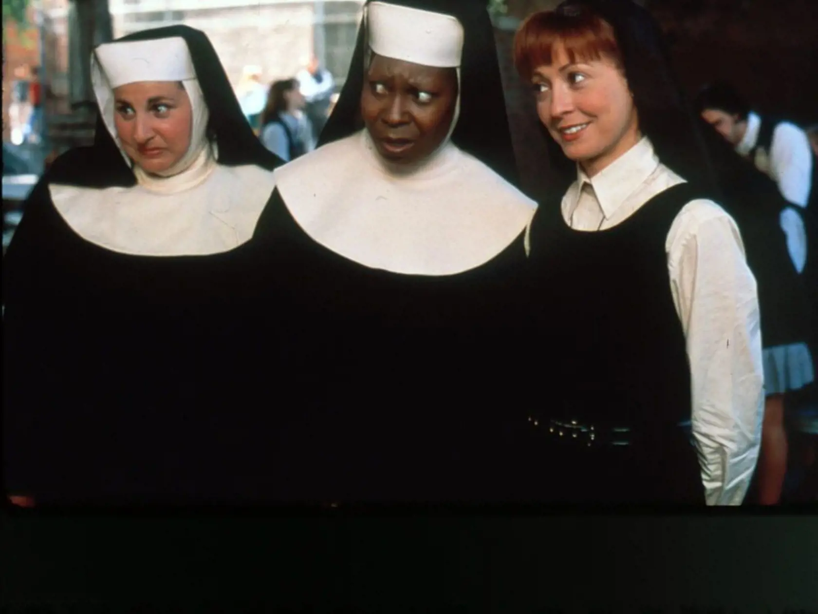 Speváčka prezlečená za mníšku (Whoopi Goldberg, v strede) ich naučila spievať. 