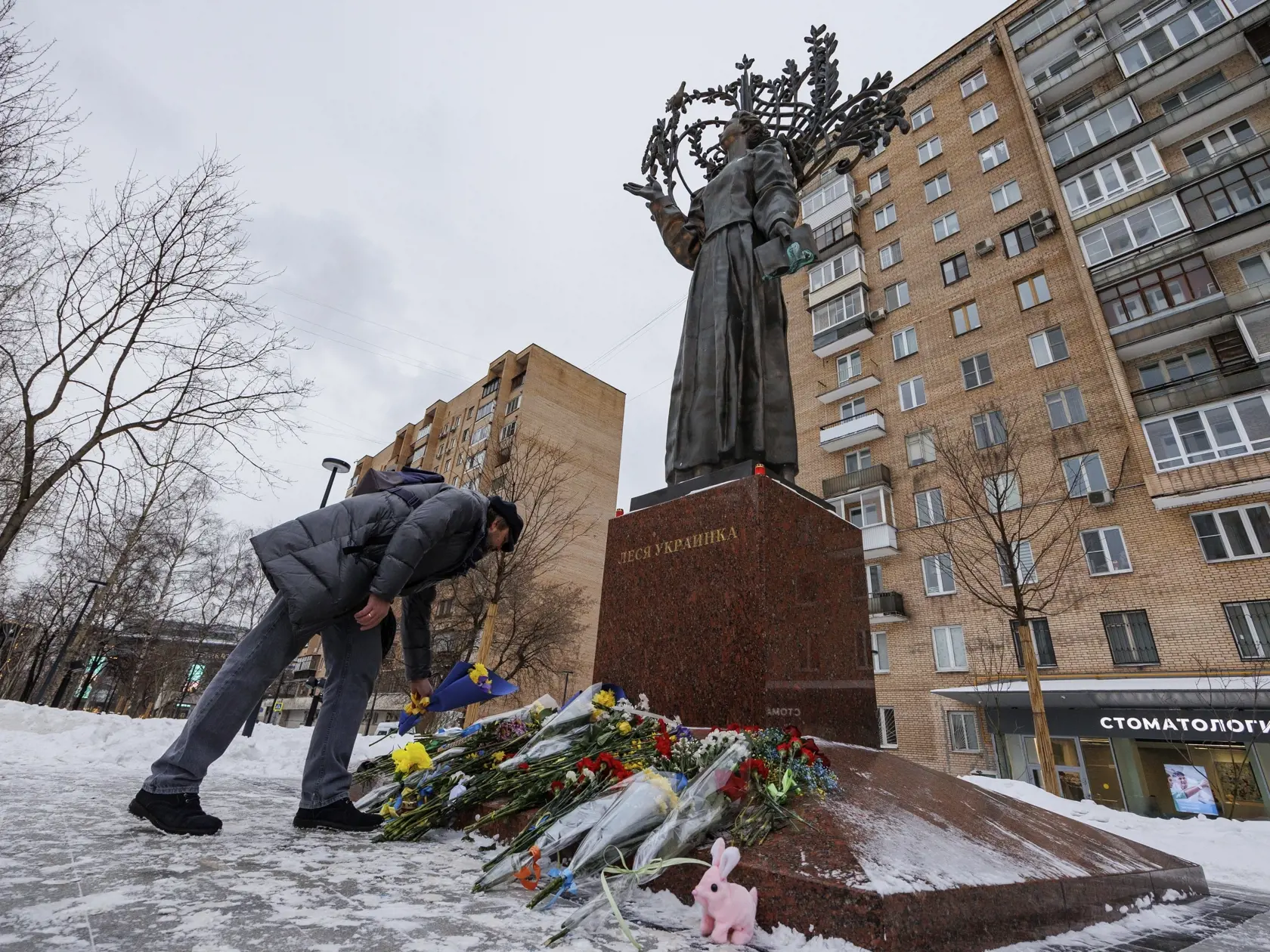 Muž kladie kvety pred sochu ukrajinskej spisovateľky Lesie Ukrajinky počas prvého výročia ruskej agresie na Ukrajine 24. februára 2023 v Moskve.