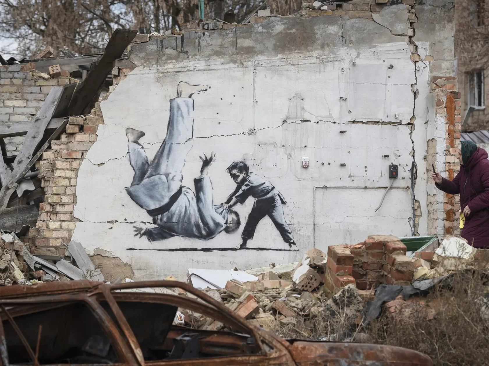 Na snímke dielo britského streetartového umelca Banksyho zobrazuje dieťa, ktoré v zápase v džude vyhráva nad ruským prezidentom Vladimirom Putinom, na budove poškodenej ostreľovaním 13. novembra 2022 v ukrajinskom meste Boroďanka.