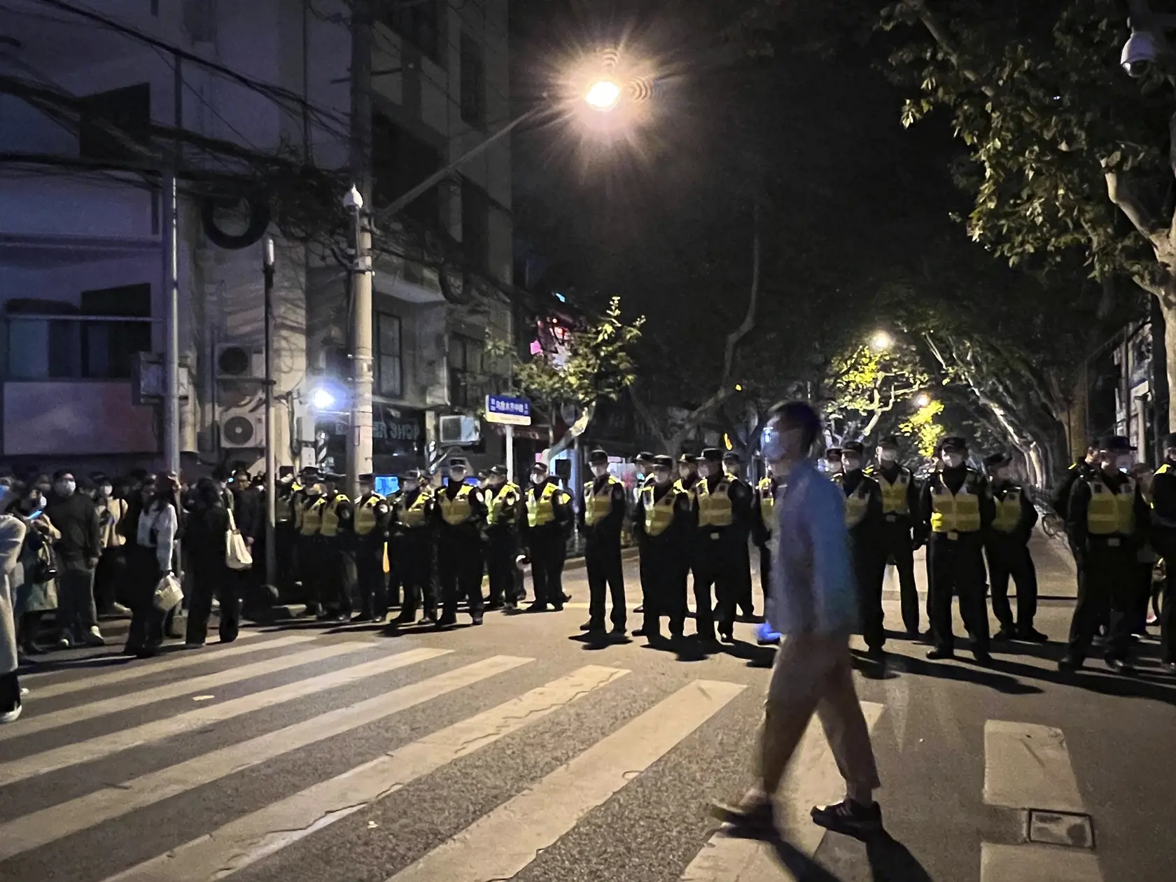 JB 49 Šanghaj - Čínski policajti blokujú miesto, kde sa zhromažďujú demonštranti počas protestu proti covidovým opatreniam v čínskom Šanghaji 27. novembra 2022. Do ulíc najväčšieho čínskeho mesta Šanghaj vyšli v nedeľu ráno demonštranti, ktorí požadovali ukončenie prísnych opatrení proti šíreniu covidu. Protest zorganizovali aj študenti elitnej univerzity v čínskej metropole Peking, informuje agentúra AFP. Protestné zhromaždenia vypukli v reakcii na tohtotýždňový smrtiaci požiar v čínskom región