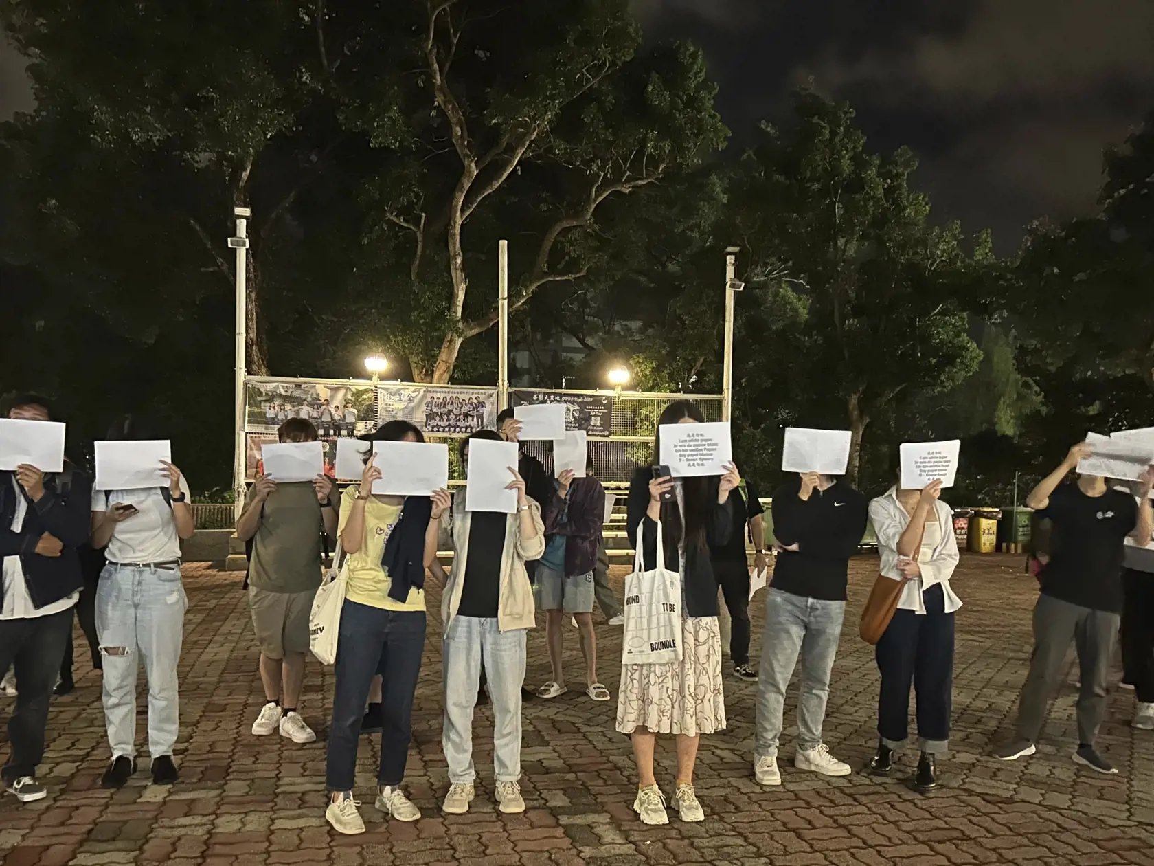 KK27 Hongkong - Protestujúci držia pred tvárou hárok papiera počas spomienky za obete požiaru výškovej budovy v Urumči na severozápade Číny 28. novembra 2022 v Hongkongu. Desiatky ľudí sa v pondelok zhromaždili na jednom z najväčších univerzitných kampusov v Hongkongu, aby vyjadrili svoj nesúhlas s prísnymi proticovidovými opatreniami vo zvyšku Číny. Zo sviečok vytvorili číslo 1124, ktoré symbolizuje 24. november, keď pri požiari výškovej budovy v Urumči na severozápade krajiny zahynulo desať ľu
