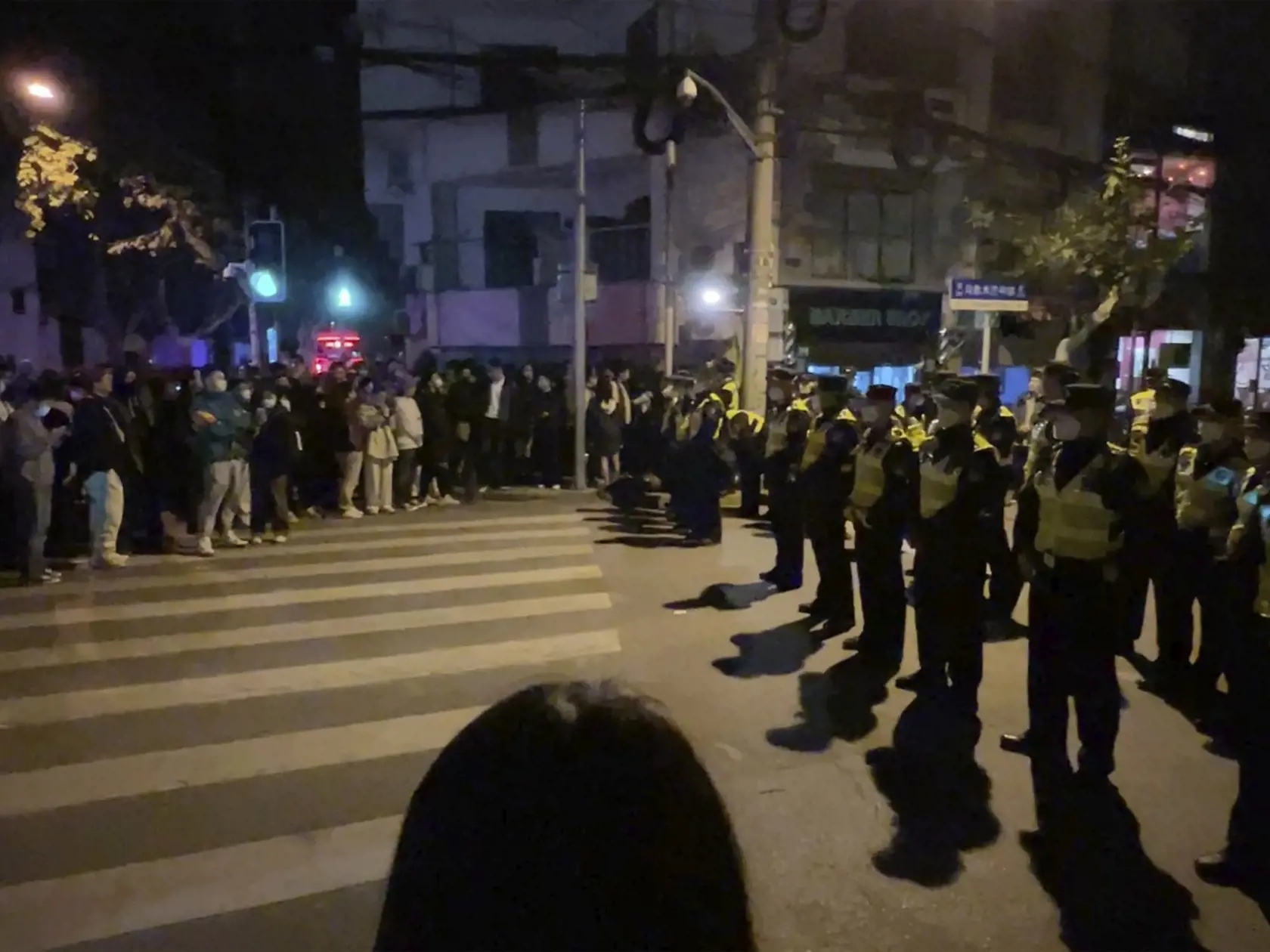 JB 52 Šanghaj - Čínski policajti blokujú miesto, kde sa zhromažďujú demonštranti počas protestu proti covidovým opatreniam v čínskom Šanghaji 27. novembra 2022. Do ulíc najväčšieho čínskeho mesta Šanghaj vyšli v nedeľu ráno demonštranti, ktorí požadovali ukončenie prísnych opatrení proti šíreniu covidu. Protest zorganizovali aj študenti elitnej univerzity v čínskej metropole Peking, informuje agentúra AFP. Protestné zhromaždenia vypukli v reakcii na tohtotýždňový smrtiaci požiar v čínskom región