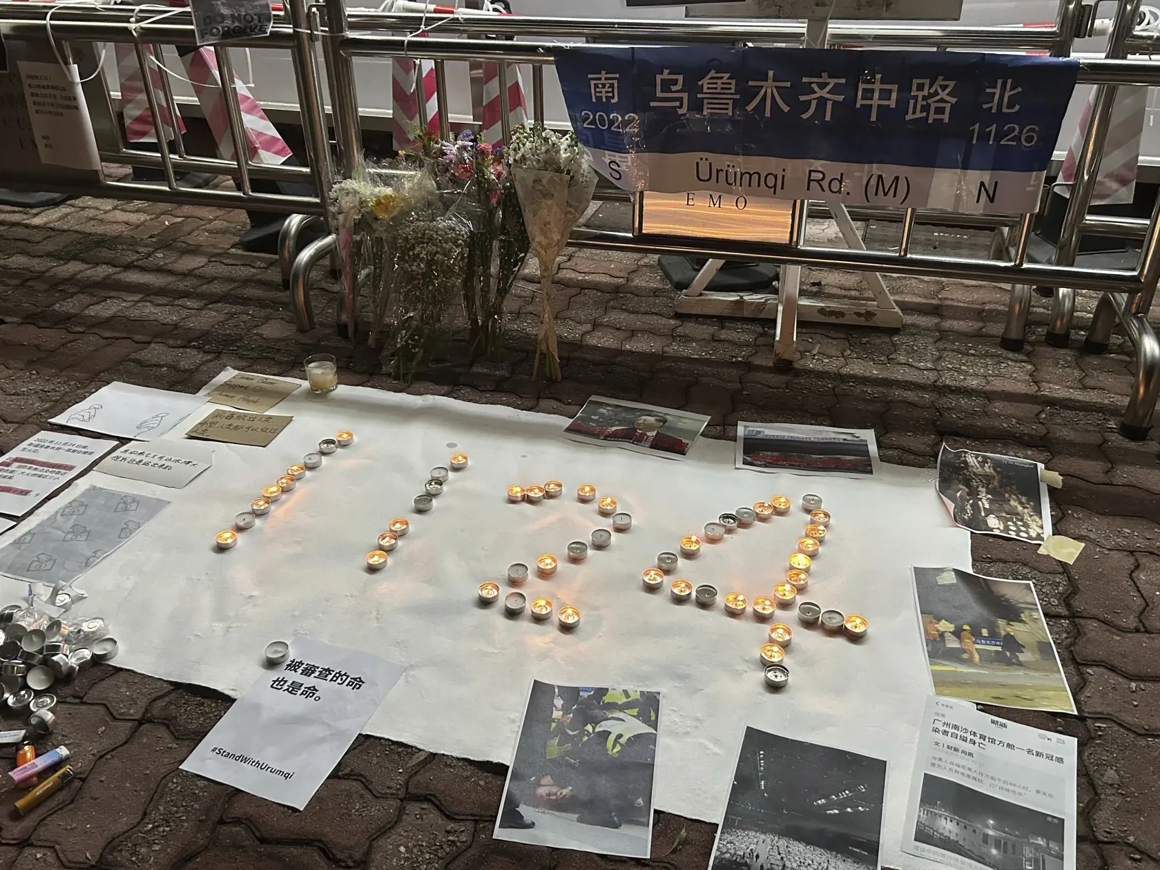 KK26 Hongkong - Sviečky sú uložené do tvaru čísla 1124 , ktoré symbolizuje 24. november, keď pri požiari výškovej budovy v Urumči na severozápade krajiny zahynulo desať ľudí, počas spomienky na obete požiaru 28. novembra 2022 v Hongkongu. Desiatky ľudí sa v pondelok zhromaždili na jednom z najväčších univerzitných kampusov v Hongkongu, aby vyjadrili svoj nesúhlas s prísnymi proticovidovými opatreniami vo zvyšku Číny. FOTO TASR/AP
A printout of the Urumqi road sign and candles laid out to represe