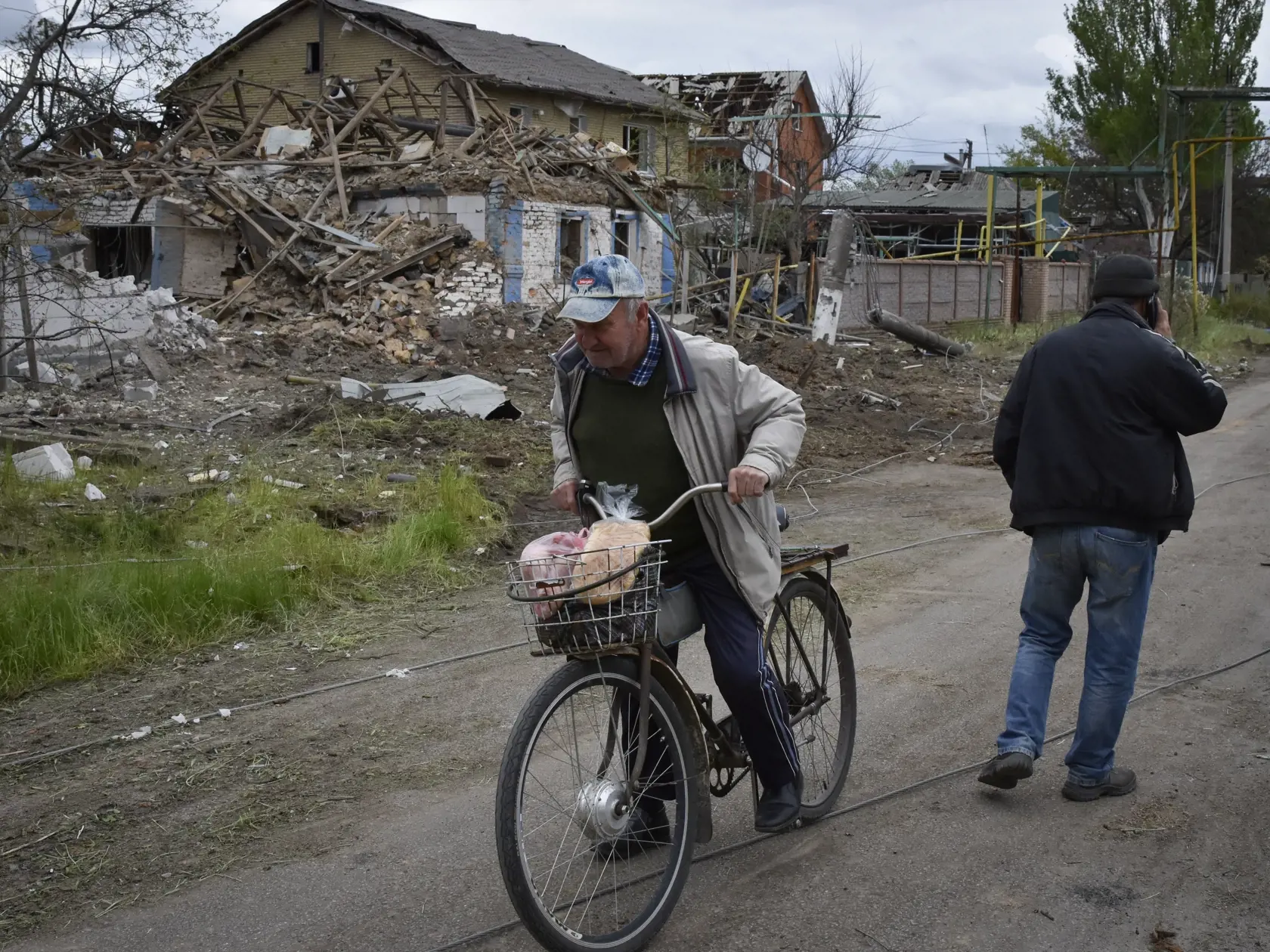 Miestny obyvateľ nasadá na bicykel pri zničených domoch po útoku ruskej armády v ukrajinskom meste Orichiv v Záporožskej oblasti v stredu 10. mája 2023.