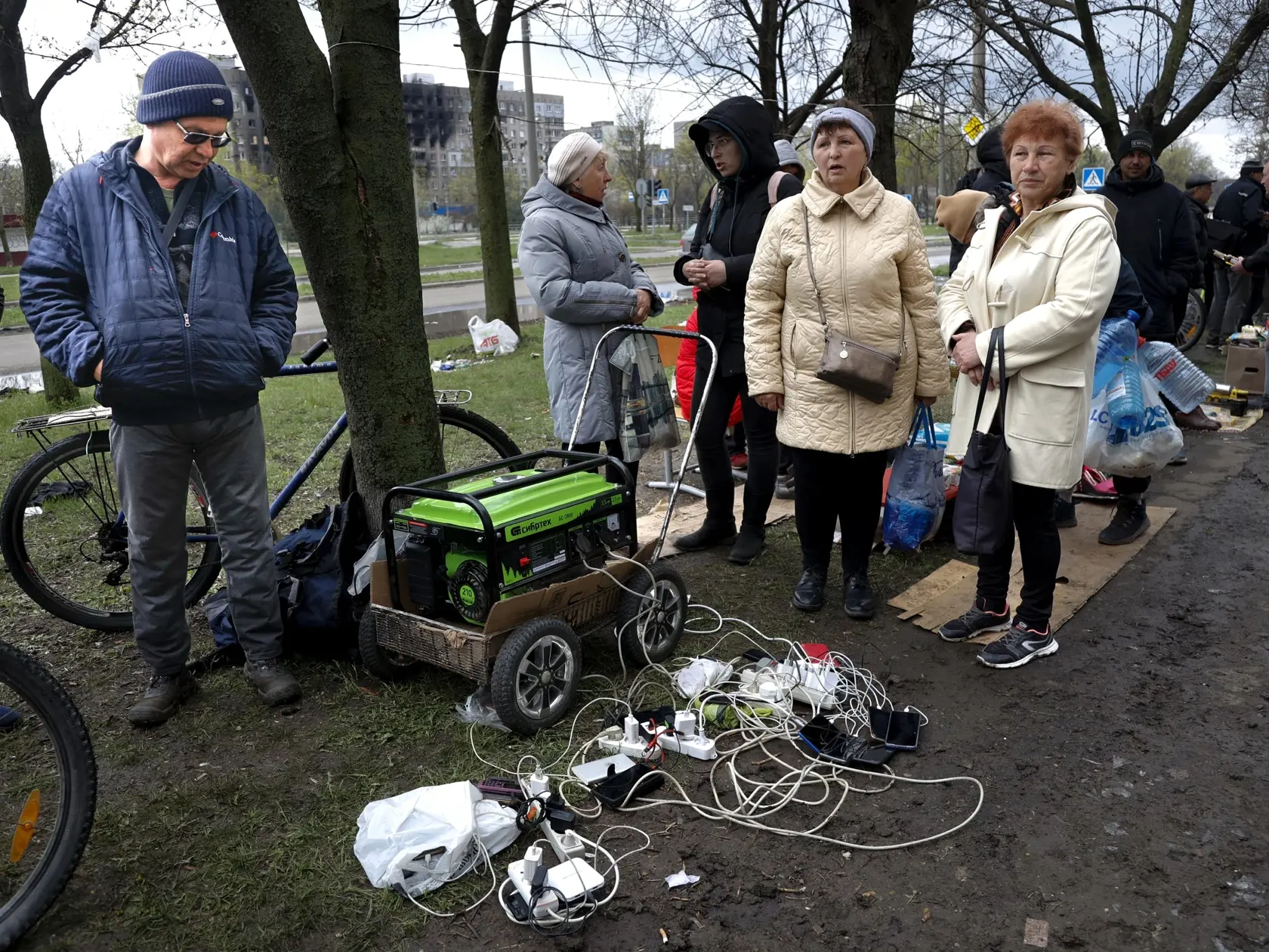 EBE 26 Mariupol - Ukrajina v sobotu napoludnie podnikne nový pokus o evakuáciu civilistov z obliehaného prístavného mesta Mariupol. Na snímke miestni obyvatelia sa zhromažďujú pri generátore, aby nabili svoje mobilné zariadenia v Mariupole na Ukrajine 22. apríla 2022. 
Local residents gather near a generator to charge their mobile devices in an area controlled by Russian-backed separatist forces in Mariupol, Ukraine, Friday, April 22, 2022. (AP Photo/Alexei Alexandrov)