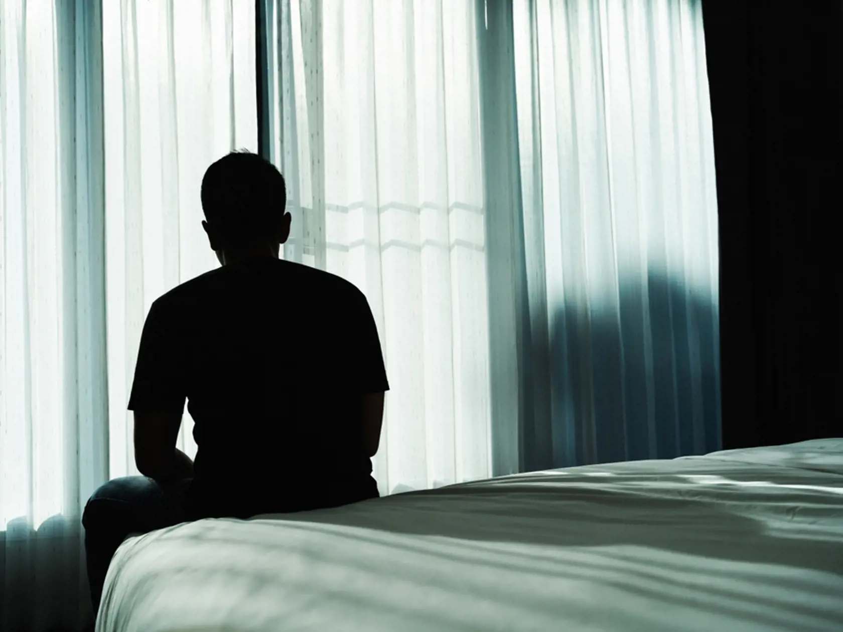 Silhouette,Depressed,Man,Sadly,Sitting,On,The,Bed,In,The