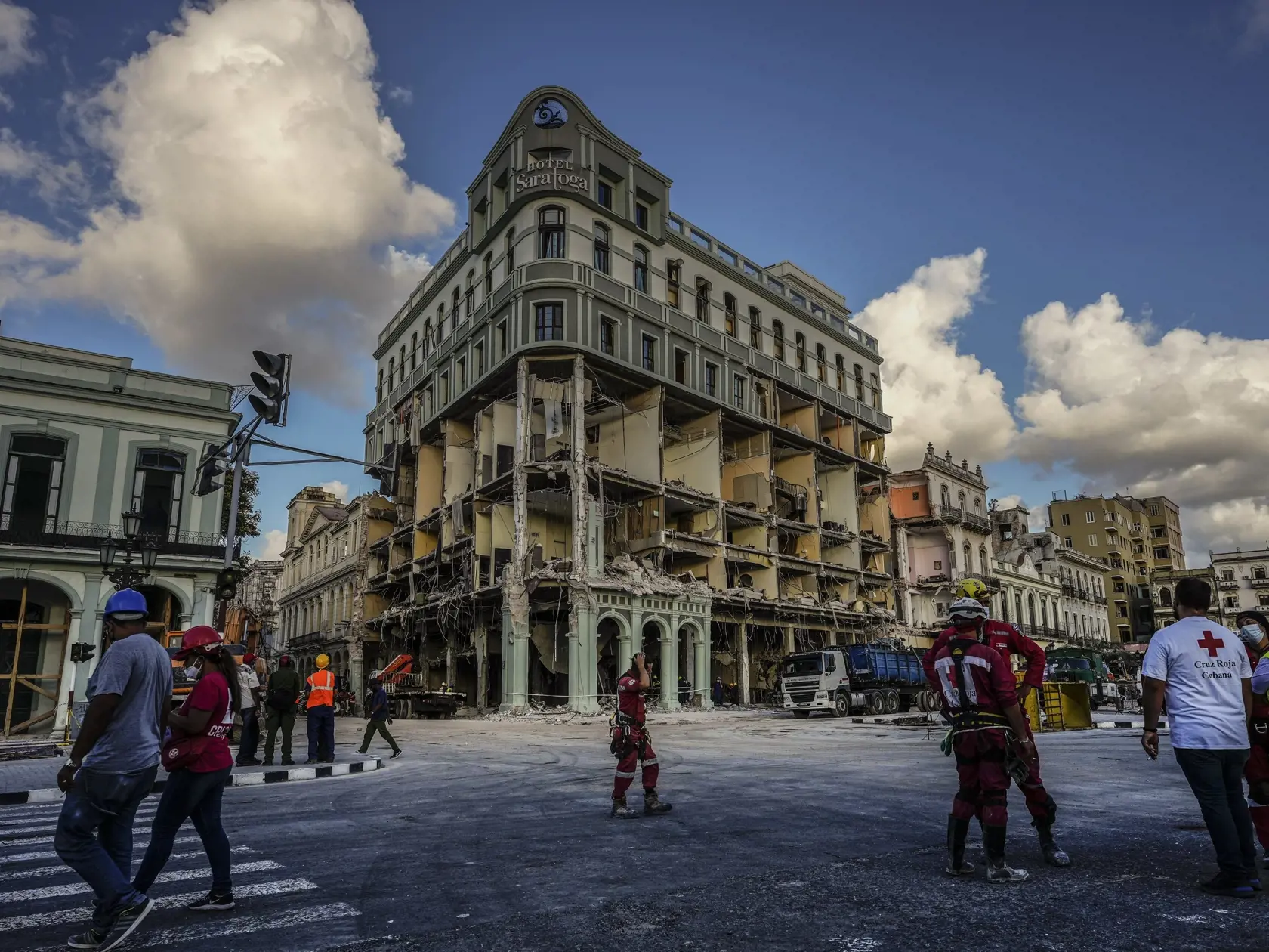 WA 60 Havana - Záchranári a príslušníci kubánskeho červeného kríža kráčajú pred luxusným hotelom Saratoga v Havane v stredu 11. mája 2022, ktorý zničila minulý týždeň explózia. V hoteli postavenom v 19. storočí podľa AFP prebiehali renovačné práce, a tak v ňom neboli ubytovaní nijakí hostia. V jeho blízkosti sa nachádza budova školy, ktorú po výbuchu preventívne evakuovali. V hoteli Saratoga sa podľa jeho webovej stránky nachádza 96 izieb, dve reštaurácie, dva bary a strešný bazén. V minulosti v