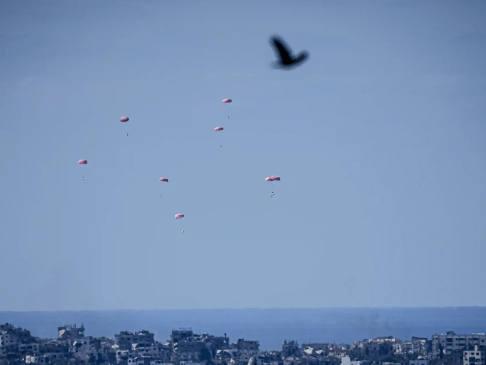 Padáky s humanitárnou pomocou sú vyhadzované na sever pásma Gazy, čo je viditeľné z juhu Izraela v nedeľu 10. marca 2024. Izraelská armáda bojuje s palestínskymi militantmi hnutia Hamas v pásme Gazy po útokoch Hamasu na Izrael 8. októbra.