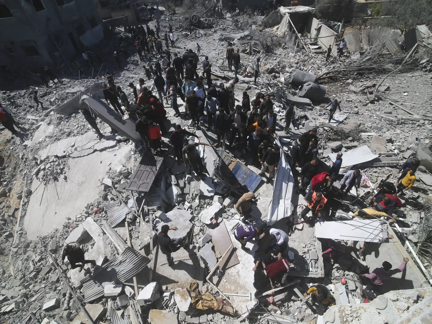 Palestínčania sa pozerajú na zničenú obytnú budovu po izraelskom bombardovaní pásma Gazy v Rafahu, na juhu pásma Gazy 20. marca 2024.