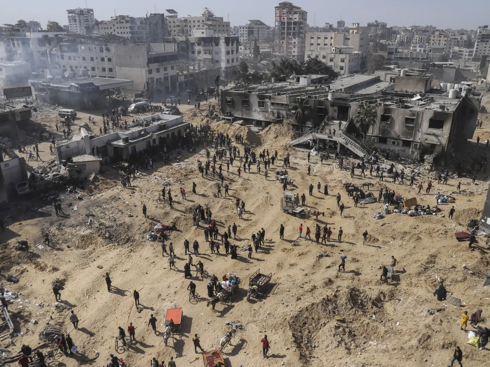 Palestínčania kráčajú po zničenom území, ktoré zanechala izraelská letecká a pozemná ofenzíva neďaleko nemocnice Šifa v meste Gaza v Pásme Gazy v pondelok 1. apríla 2024.  Izraelská armáda v pondelok potvrdila ukončenie svojej dvojtýždňovej operácie v okolí nemocnice a stiahnutie svojich vojakov. Nemocnica Šifá je  najväčšie zdravotnícke zariadenie v Pásme Gazy nachádzajúcom  sa v meste Gaza.
