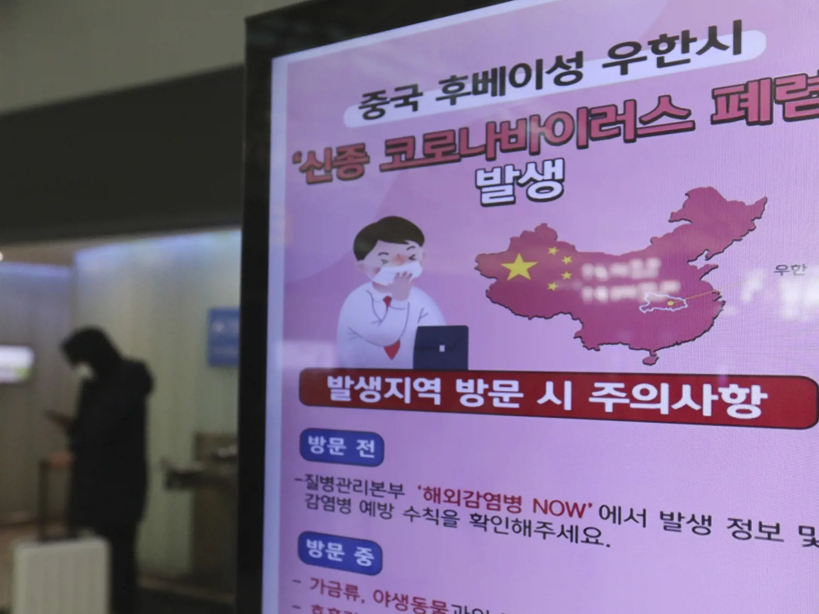 JB 33 Inčcheon - Cestujúci s ochranným rúškom na tvári stojí pri posteri s upozornením na šíriaci sa koronavírus na medzinárodnom letisku v Inčcheone 27. januára 2020. Juhokórejský prezident Mun Če-in nariadil v pondelok dôkladnú kontrolu všetkých ľudí prichádzajúcich zo stredočínskeho mesta Wu-chan, odkiaľ sa začala šíriť nákaza novým smrtiacim koronavírusom. V Južnej Kórei potvrdili počas pondelka štvrtý prípad tohto ochorenia. FOTO TASR/AP

A poster warning about coronavirus is displayed in a