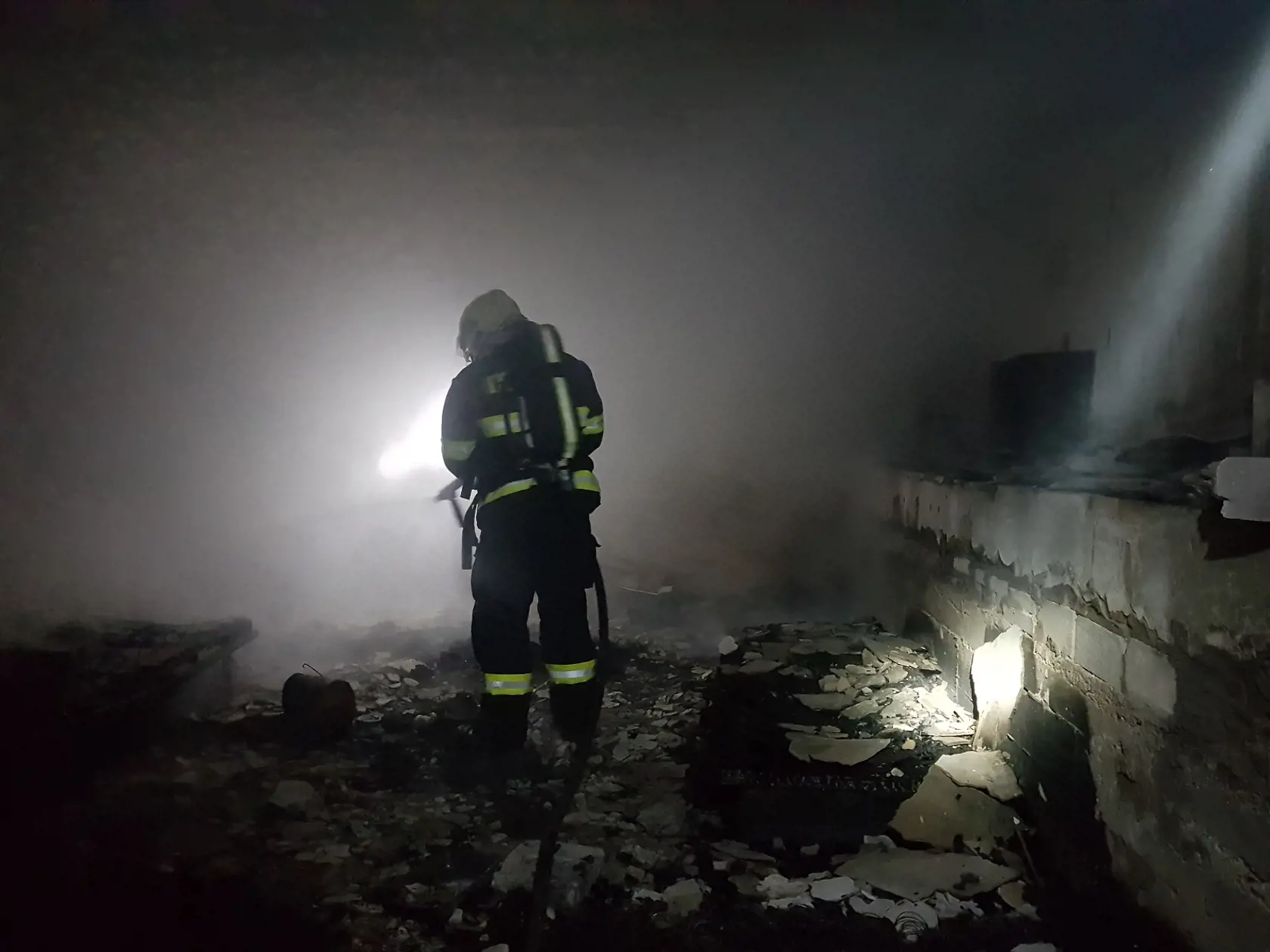 Hasiči prehľadávajú obhorenú budovu.
