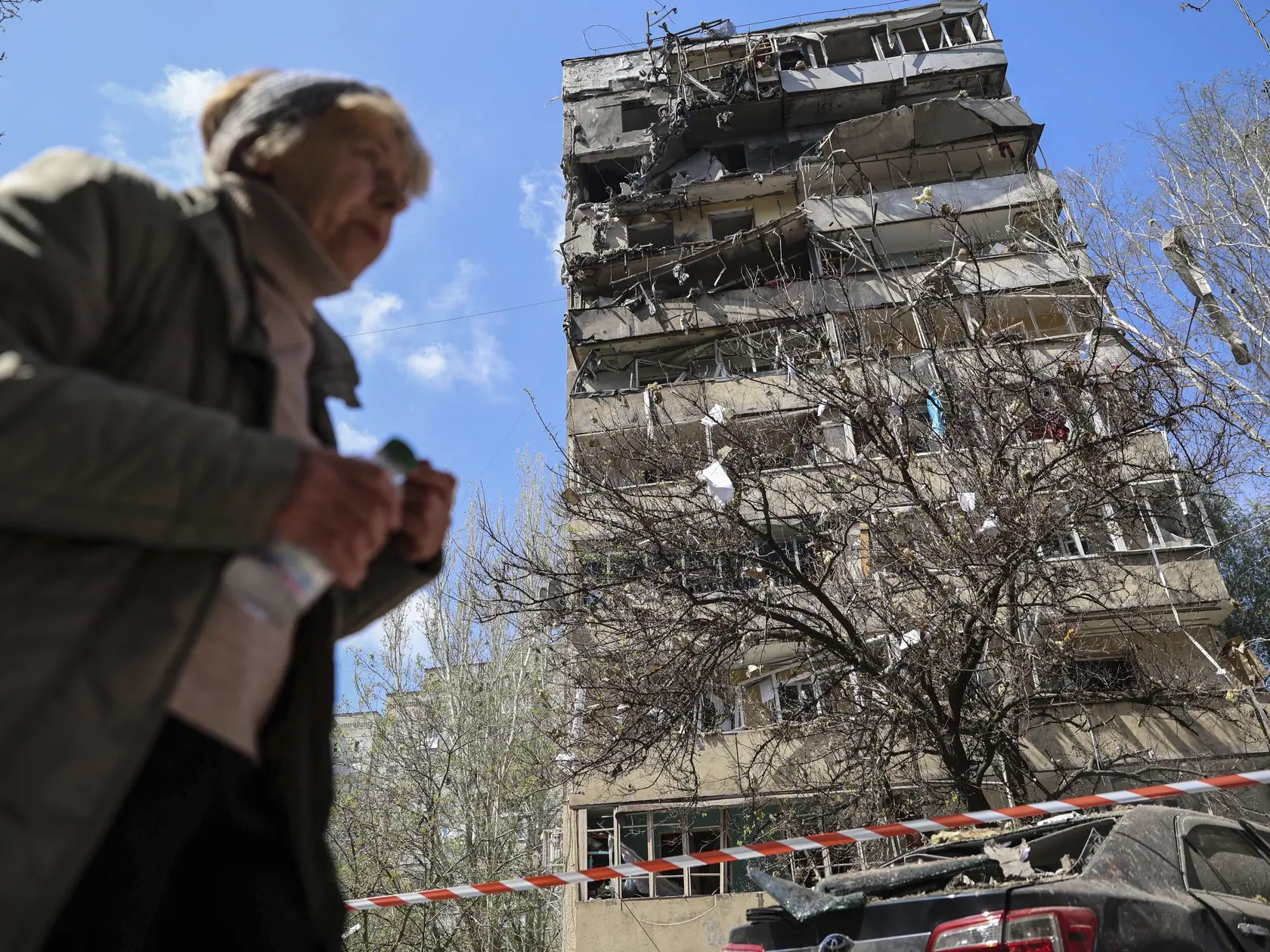 Na snímke žena kráča okolo viacposchodovej budovy, ktorú zasiahol útok ruskej armády na obytnú štvrť mesta Záporožie na juhovýchode Ukrajiny v utorok 22. apríla 2025.
