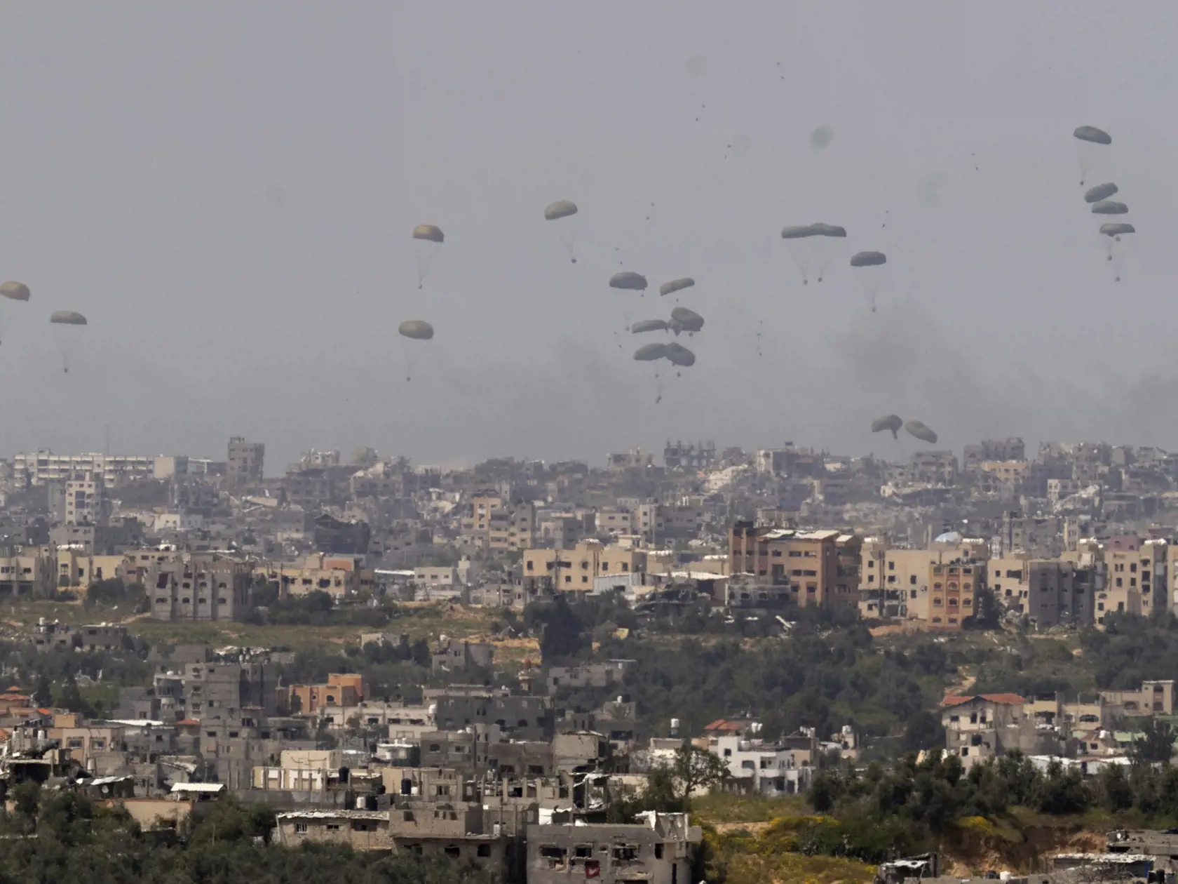 Padáky s humanitárnou pomocou nad severom pásma Gazy, čo je viditeľné z juhu Izraela v stredu 27. marca 2024. Izraelská armáda bojuje s palestínskymi militantmi hnutia Hamas v pásme Gazy po útokoch Hamasu na Izrael 8. októbra.