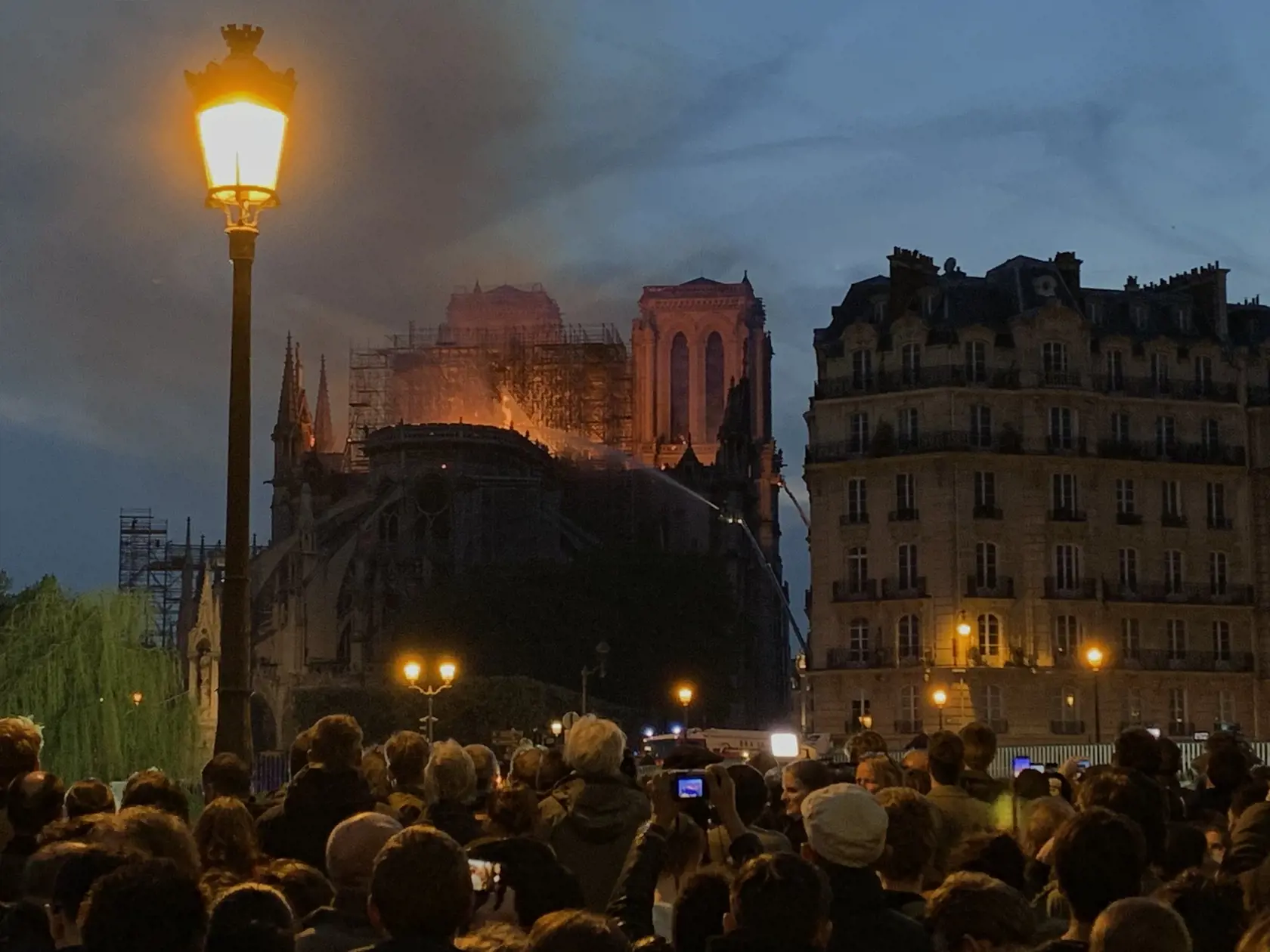 Obyvatelia Paríža sledujú boj hasičov s plameňmi, ktoré postupne zožierajú pýchu Francúzska.