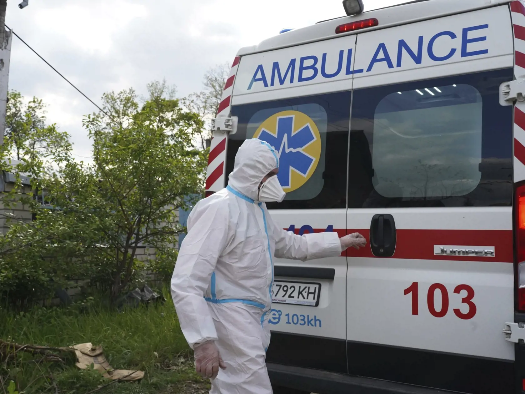 Dobrovoľník odetý v špeciálnom ochrannom odeve zatvára zadné dvere sanitky, ktorá odváža telá zabitých ruských vojakov v dedine Malaja Rohan v Charkovskej oblasti počas 85. dňa ruskej invázie na Ukrajinu vo štvrtok 19. mája 2022.