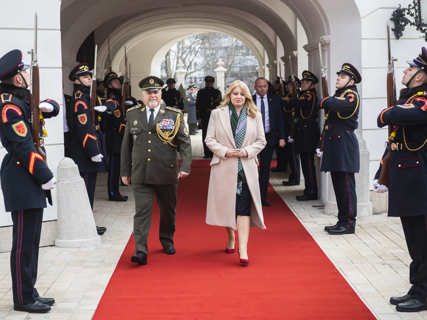 Vľavo generálmajor Ozbrojených síl SR vo výslužbe Ondřej Novosad v Bratislave 16. februára 2023. Prezidentka kráča so zopnutými rukami a rozopnutým kabátom.