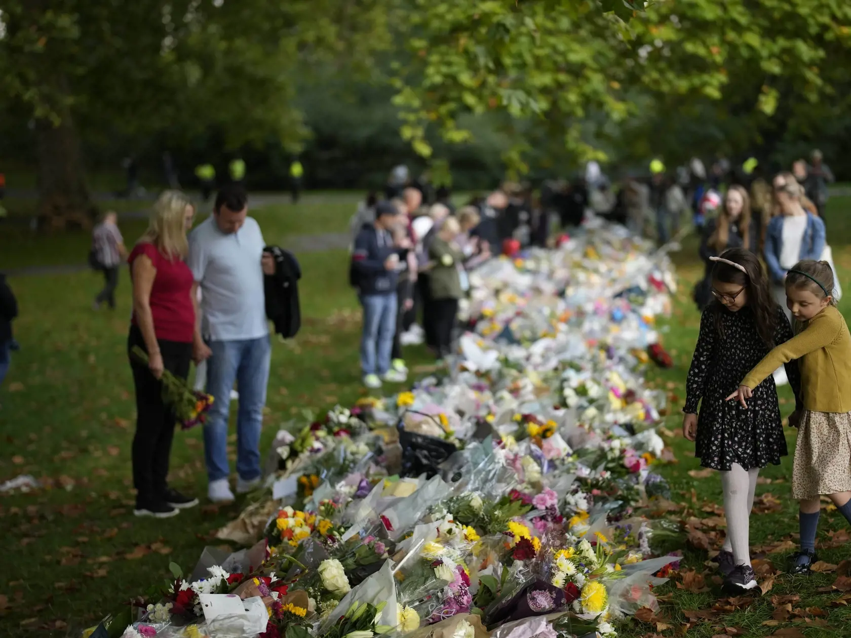 Na snímke stoja pri kvetoch na pamiatku zosnulej britskej kráľovnej Alžbety II. v The Green Park neďaleko Buckinghamského paláca v Londýne 10. septembra 2022.