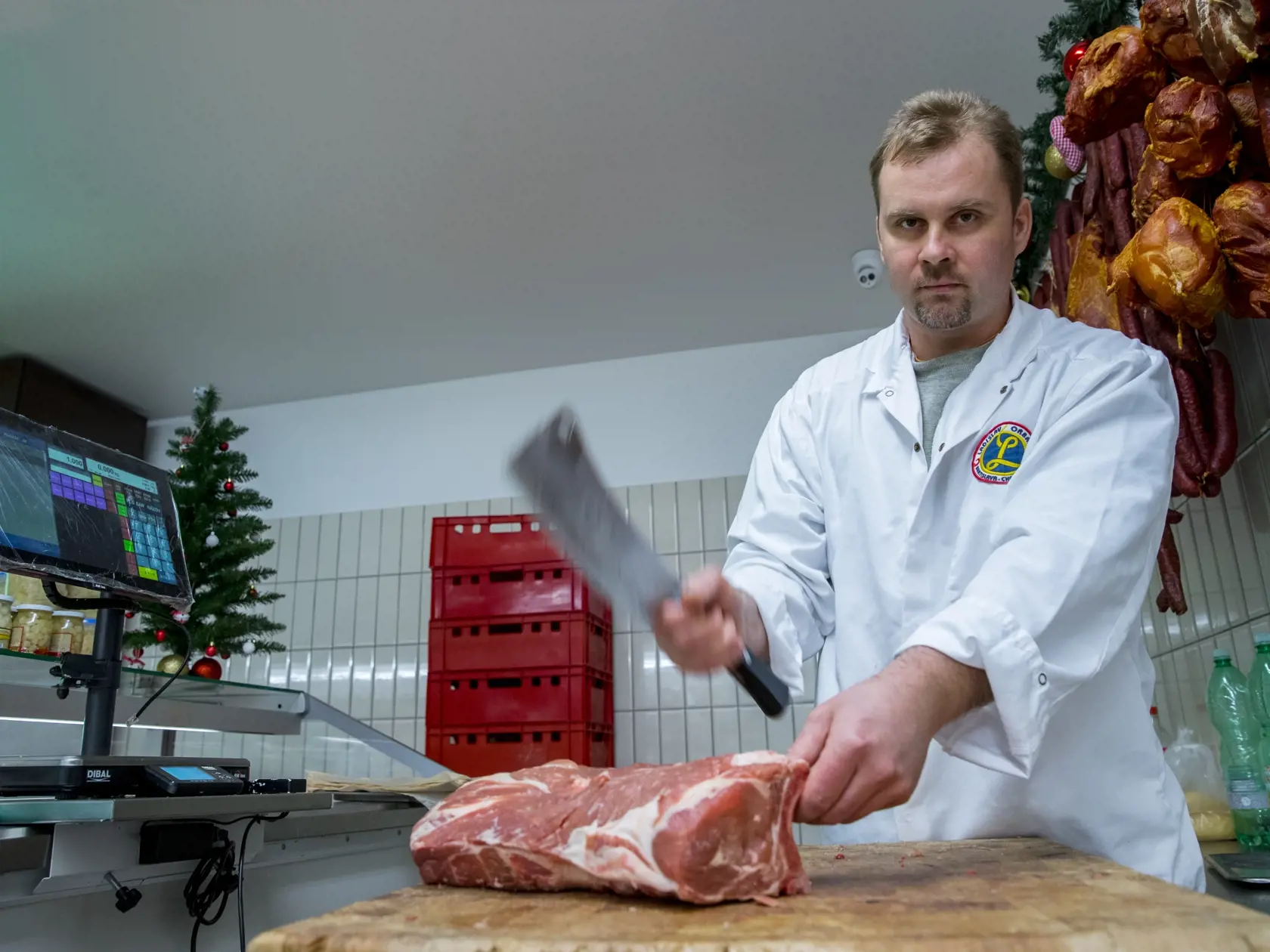 Na snimke zamestnanec predajne masa Orban Marek porcuje bravcove maso.