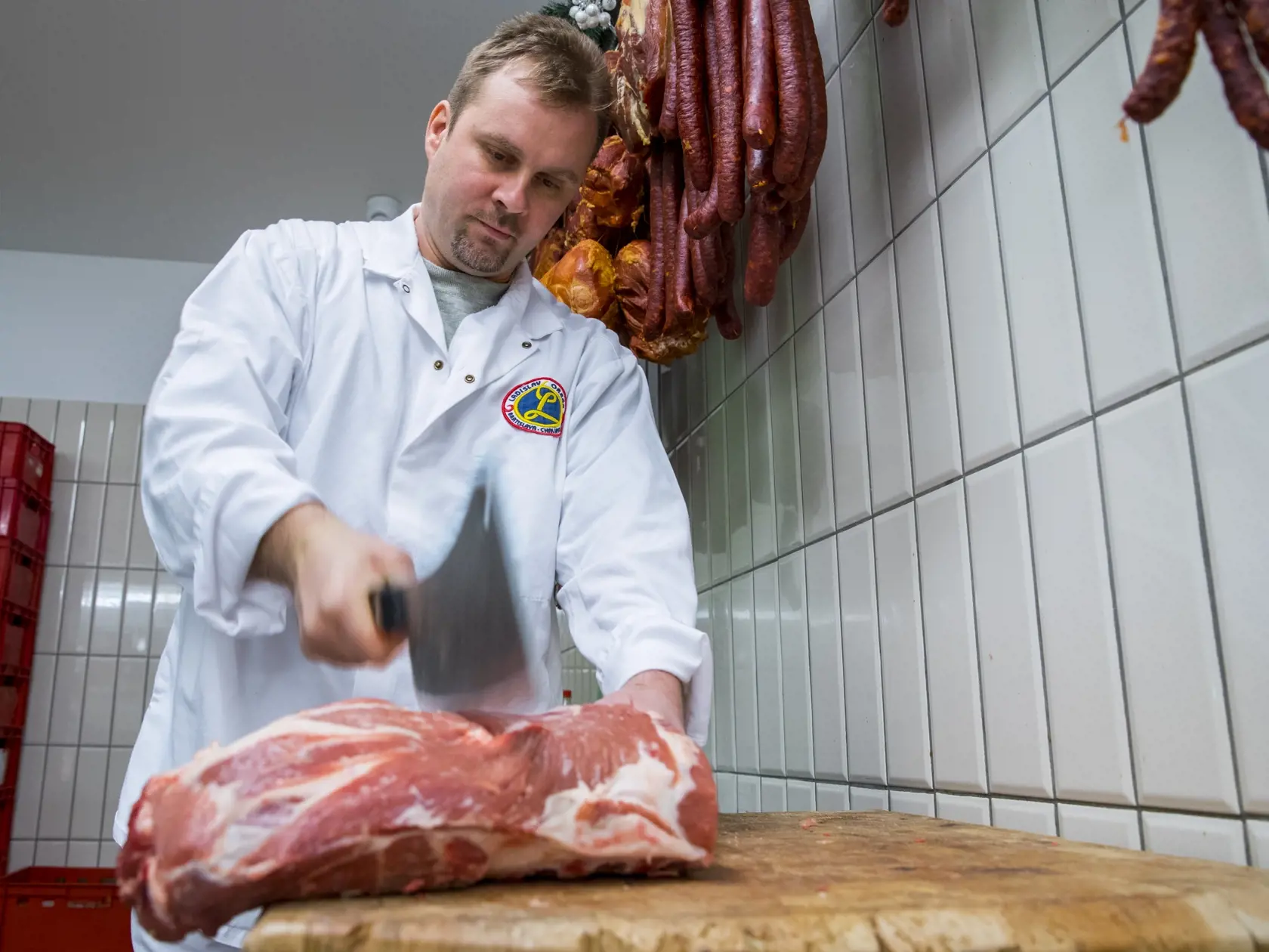 Na snimke zamestnanec predajne masa Orban Marek porcuje bravcove maso.