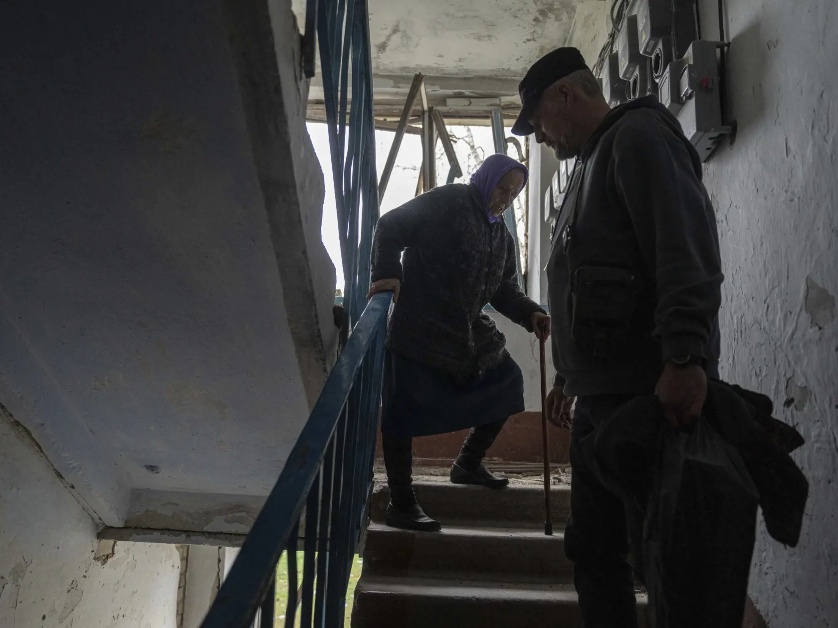KK11 Lukianci - Dobrovoľník pomáha 79-ročnej Oľge schádzať dole schodami z jej bytu, ktorý bol poškodený ruským náletom v dedine Lukianci  v Charkovskej oblasti v utorok 16. apríla 2024. FOTO TASR/AP
A volunteer helps Olga, 79, walk down the stairs from her apartment which was heavily damaged by a Russian airstrike, during her evacuation in Lukiantsi, Kharkiv region, Ukraine, on Tuesday, April 16, 2024. (AP Photo/Evgeniy Maloletka)
