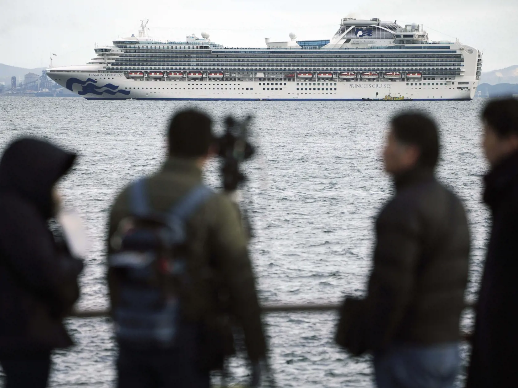 KK8 Jokohama - V pozadí výletná loď Diamond Princess kotví v prístave v Jokohame 4. februára 2020. Japonskí zdravotníci vykonávajú rozsiahle lekárske kontroly u všetkých 3 700 cestujúcich a posádky výletnej lode, ktorí sa vrátili do krajiny po tom, čo jeden cestujúci bol pozitívne testovaný na koronavírus. FOTO TASR/AP
A TV crew film a cruise ship Diamond Princess anchoring off the Yokohama Port Tuesday, Feb. 4, 2020, in Yokohama, near Tokyo. Japanese health officials are conducting extensive me