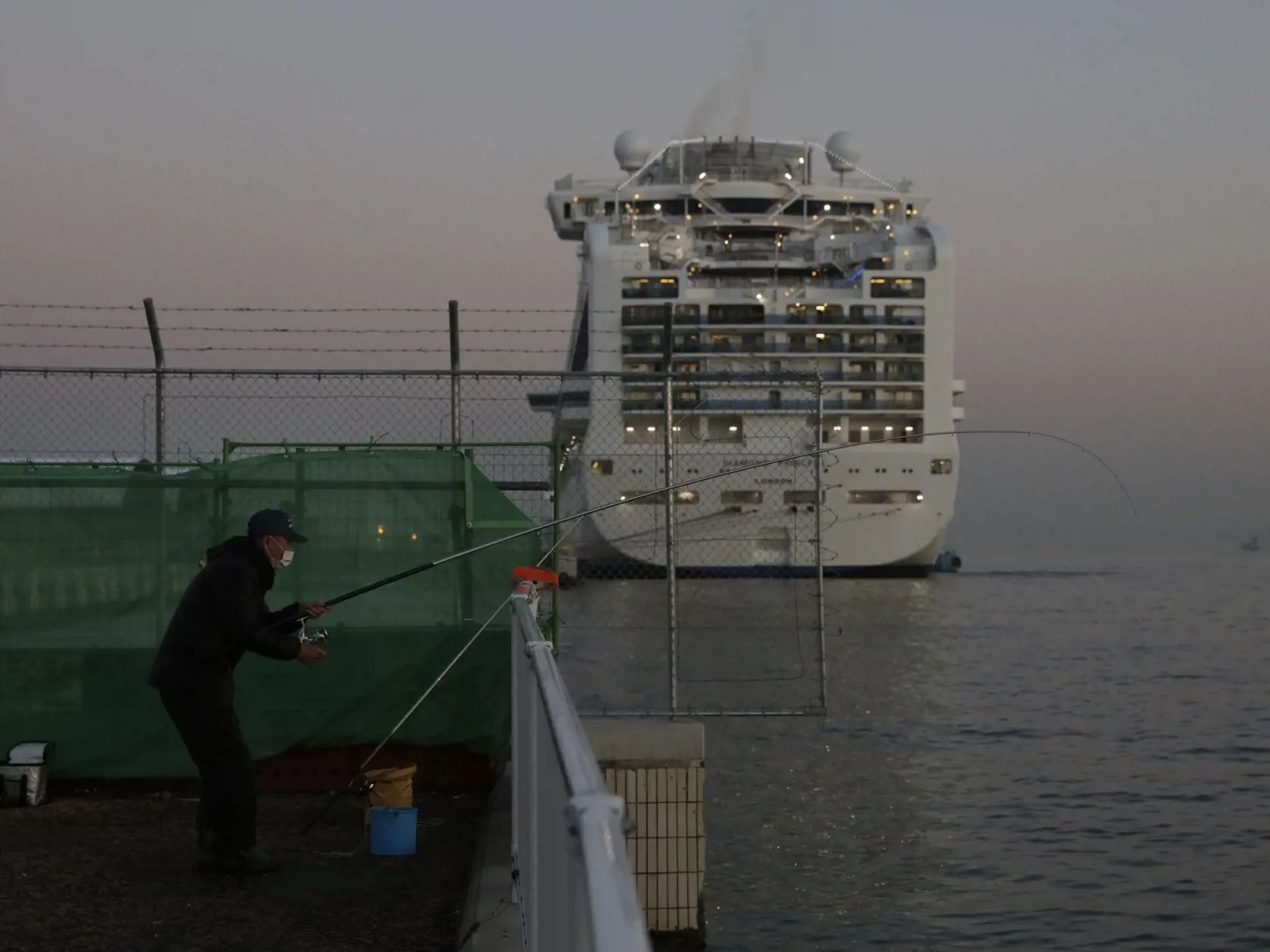 WA 30 Jokohama - Muž chytá ryby neďaleko  výletnej lode Diamond Princess, ktorá je v karanténe v japonskej Jokohame vo štvrtok 13. februára 2020. Na palube japonskej výletnej lode  sa nachádza aj Slovák. Japonské ministerstvo zdravotníctva vo štvrtok oznámilo, že ďalších 44 ľudí na palube malo pozitívne testy na nový typ koronavírusu. Na palube lode je viac ako 3500 pasažierov a členov posádky. Japonské úrady vykonali lekárske testy na 713 ľuďoch a nákazu koronavírusom potvrdili celkovo už u 218