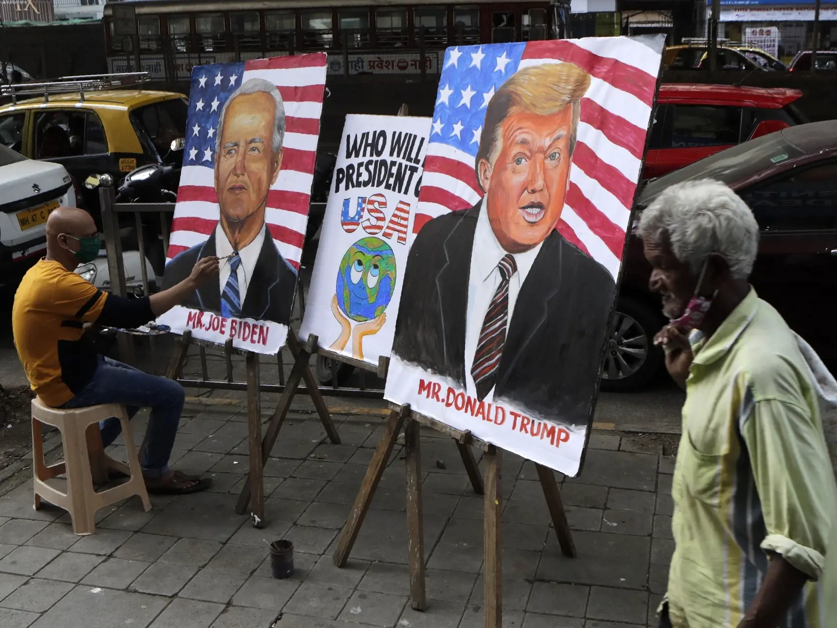 WA 38 Bombaj - Indický učiteľ umenia maľuje obrazy s podobizňou amerického prezidenta Donalda Trumpa a jeho demokratického prezidentského protikandidáta Joea Bidena na chodníku pred budovou školy v Bombaji 29. októbra 2020.