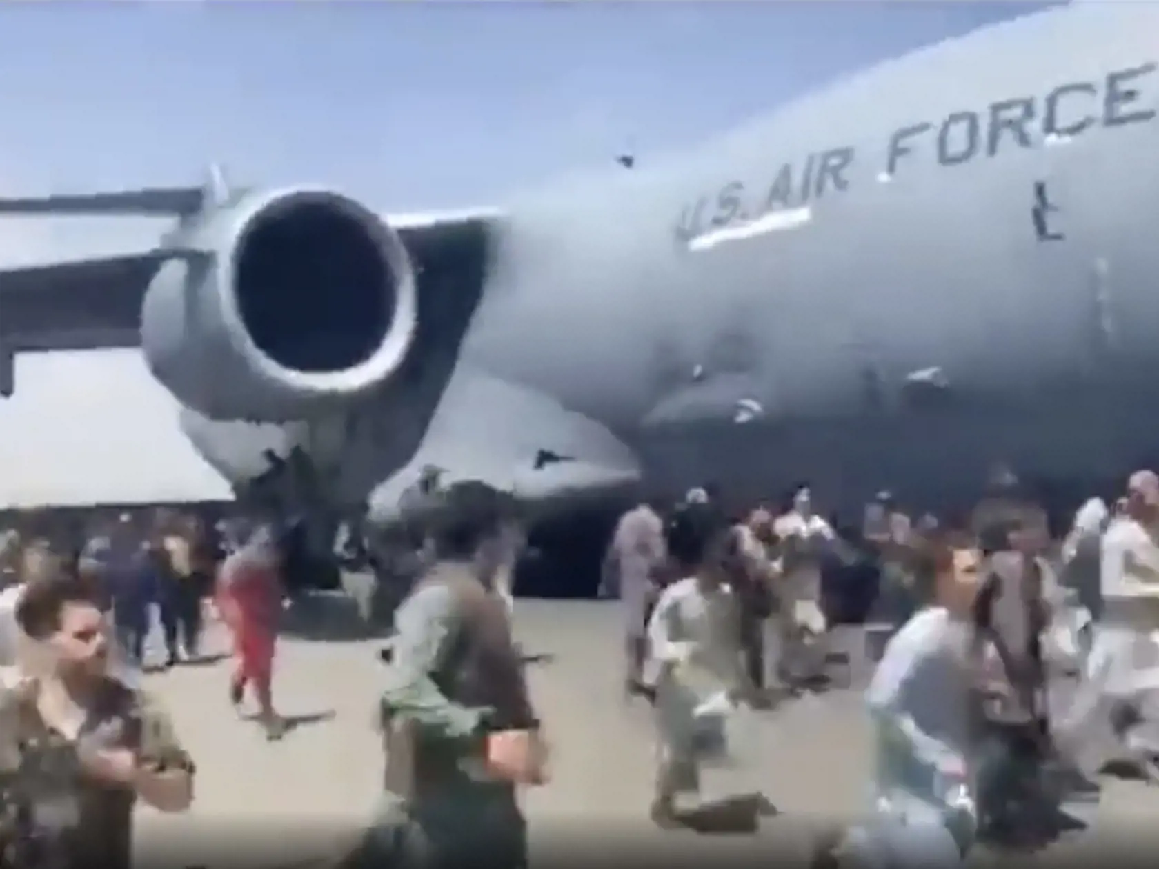 Ľudia bežia okolo amerického transportného lietadla C-17 na medzinárodnom letisku  Hámida Karzaja v Kábule 16. augusta 2021.