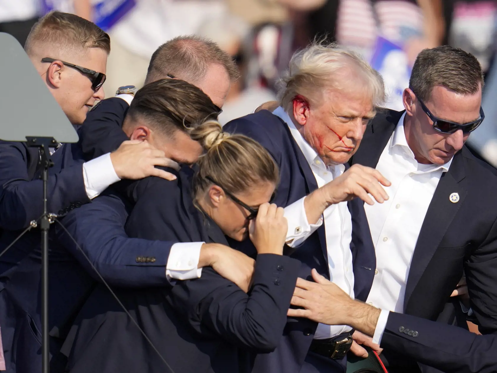 Republikánsky prezidentský kandidát Donald Trump (druhý sprava) odchádza za pomoci ochrankárov z predvolebného mítingu v meste Butler v americkom štáte Pensylvánia 13. júla 2024. Trump potvrdil, že v sobotu na mítingu v Pensylvánii ho zasiahla guľka. Tá mu prestrelila hornú časť pravého ucha. Bývalý americký prezident sa vyjadril na sociálnej sieti, informuje TASR.