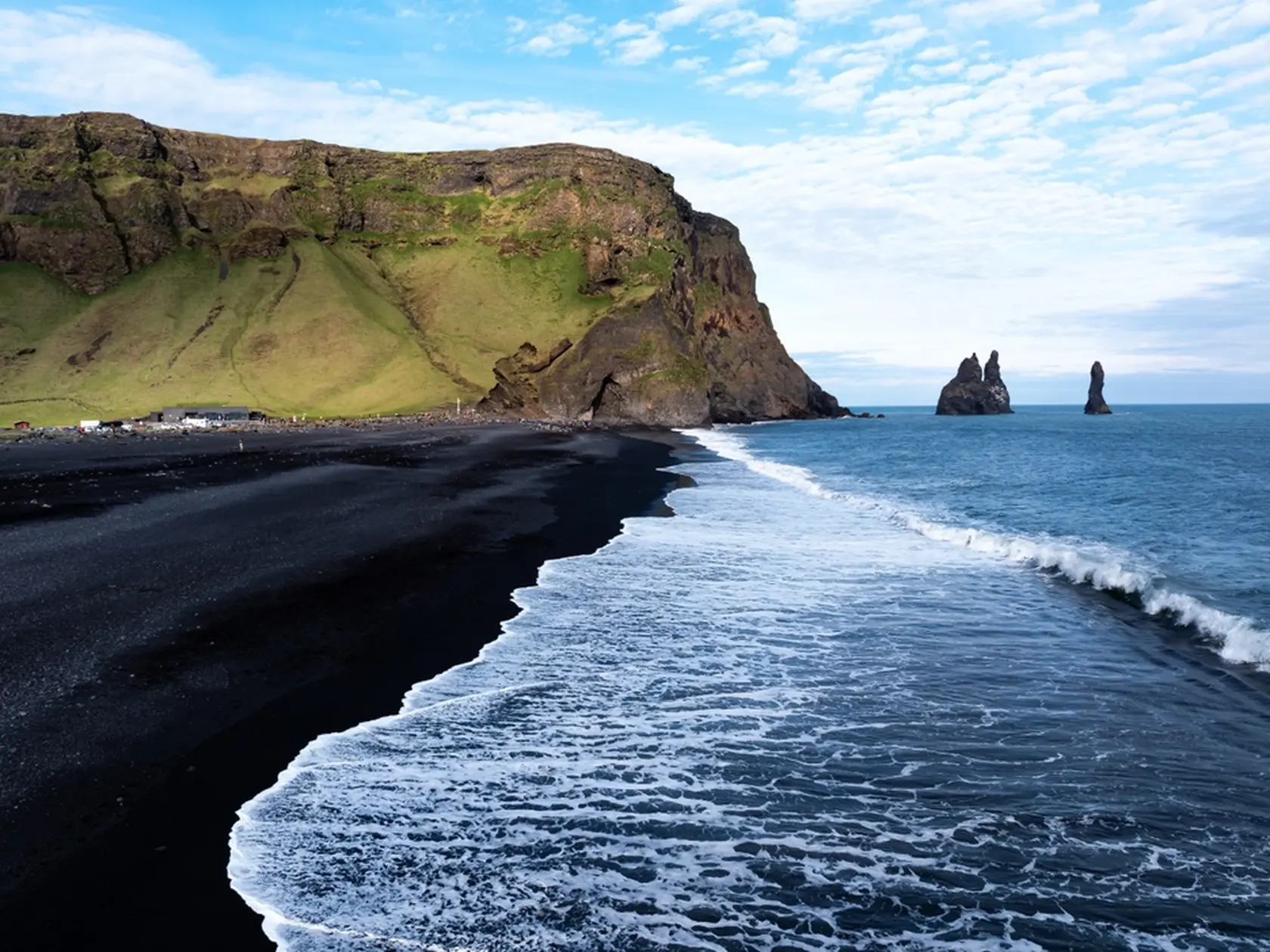 Aerial view of Reynisfjara black sand beach and sea stacks in Iceland.