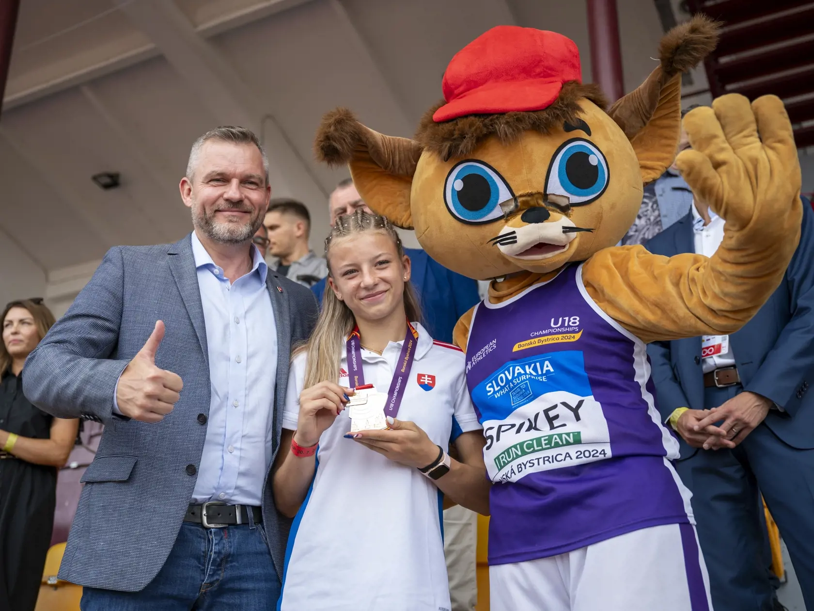 Na snímke zľava prezident Slovenskej republiky Peter Pellegrini, zlatá medailistka v behu na 100 metrov cez prekážky Laura Frličková a maskot ME Spikey počas osláv na ME do 18 rokov v Banskej Bystrici 20. júla 2024.
