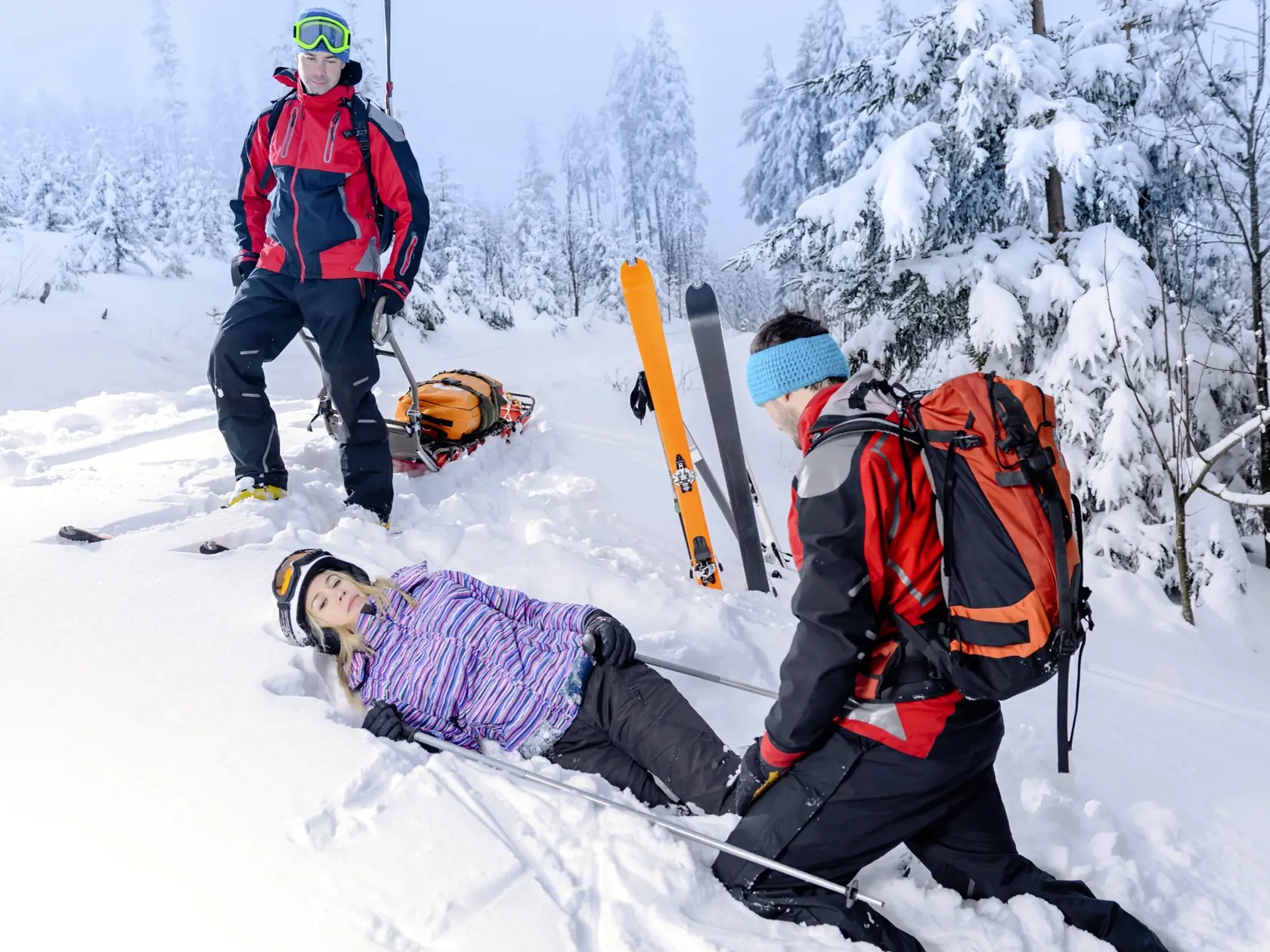 Rescue ski patrol help injured woman skier lying in snow