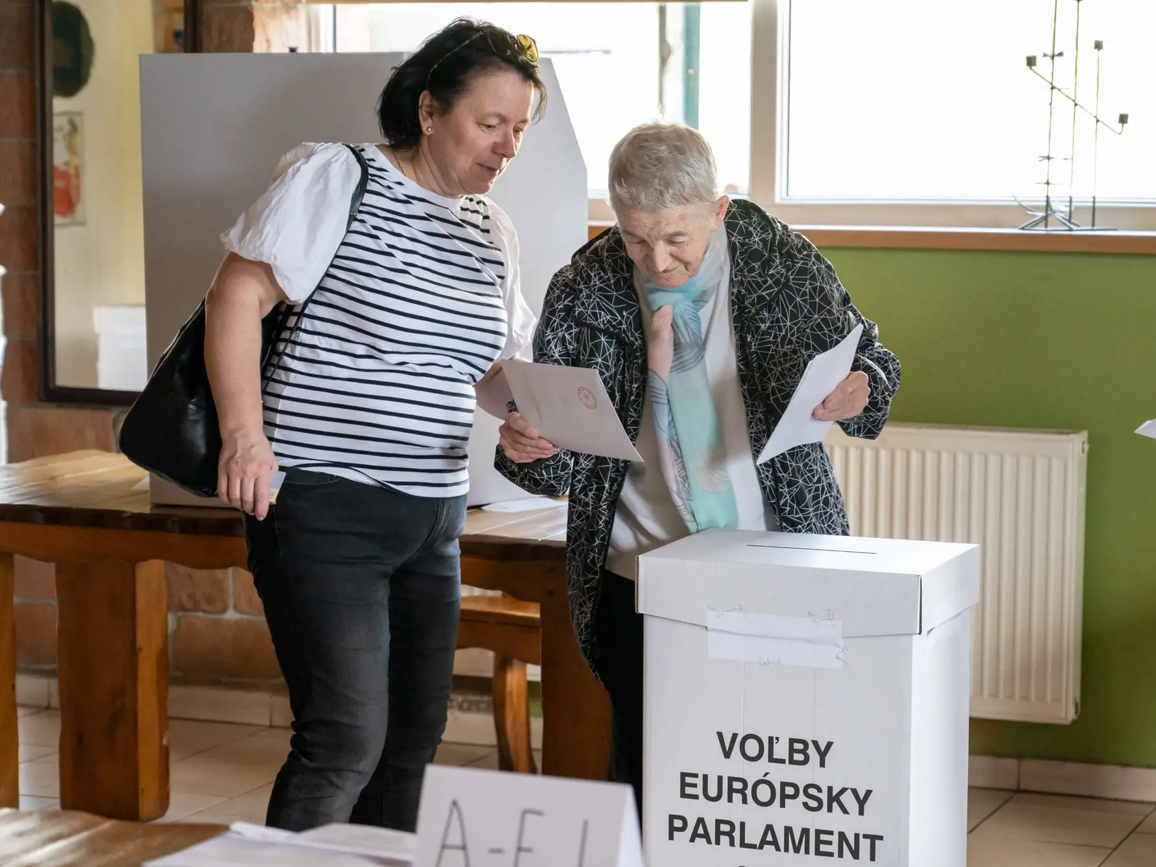 Na snímke volička s doprovodom vhadzuje obálku s hlasovacím lístkom do volebnej schránky vo voľbách do Európskeho parlamentu v zariadení U Komiňara v Prešove v sobotu 8. júna 2024.