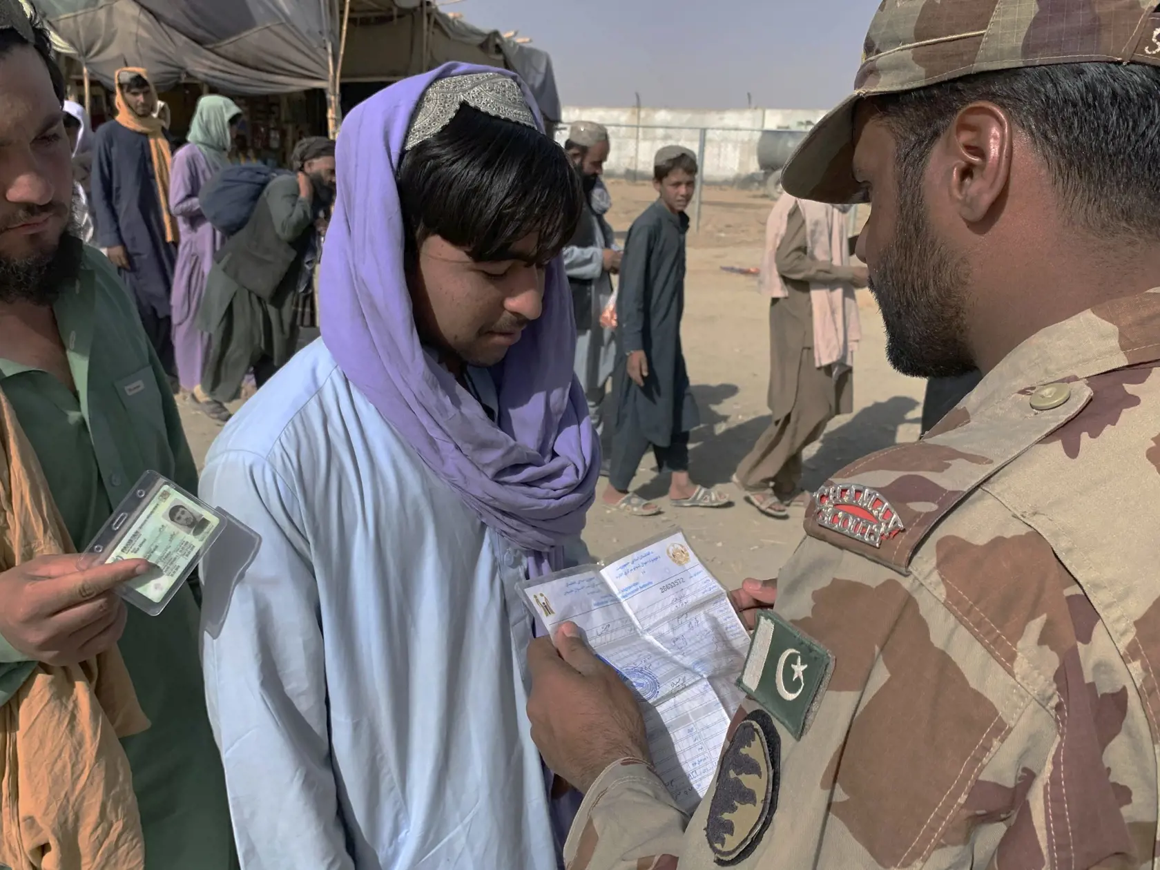 JB 24 Čaman - Pakistanský vojak kontroluje cestovné dokumenty Afgancov, ktorí opustili svoje domovy, pred prekročením hranice do Pakistanu v blízkosti hraničného priechodu medzi Pakistanom a Afganistanom, ktorý pred niekoľkými dňami zatvorili, v pakistanskom meste Čaman 26. augusta 2021. FOTO TASR/AP