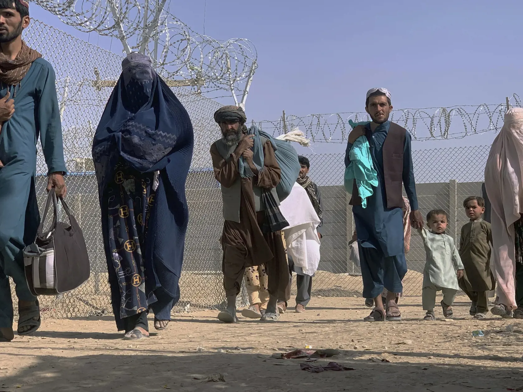 JB 22 Čaman - Afganci, ktorí opustili svoje domovy, kráčajú cez bezpečnostnú bariéru po tom, ako prekročili hranicu do Pakistanu v blízkosti hraničného priechodu medzi Pakistanom a Afganistanom, ktorý pred niekoľkými dňami zatvorili, v pakistanskom meste Čaman 26. augusta 2021. FOTO TASR/AP