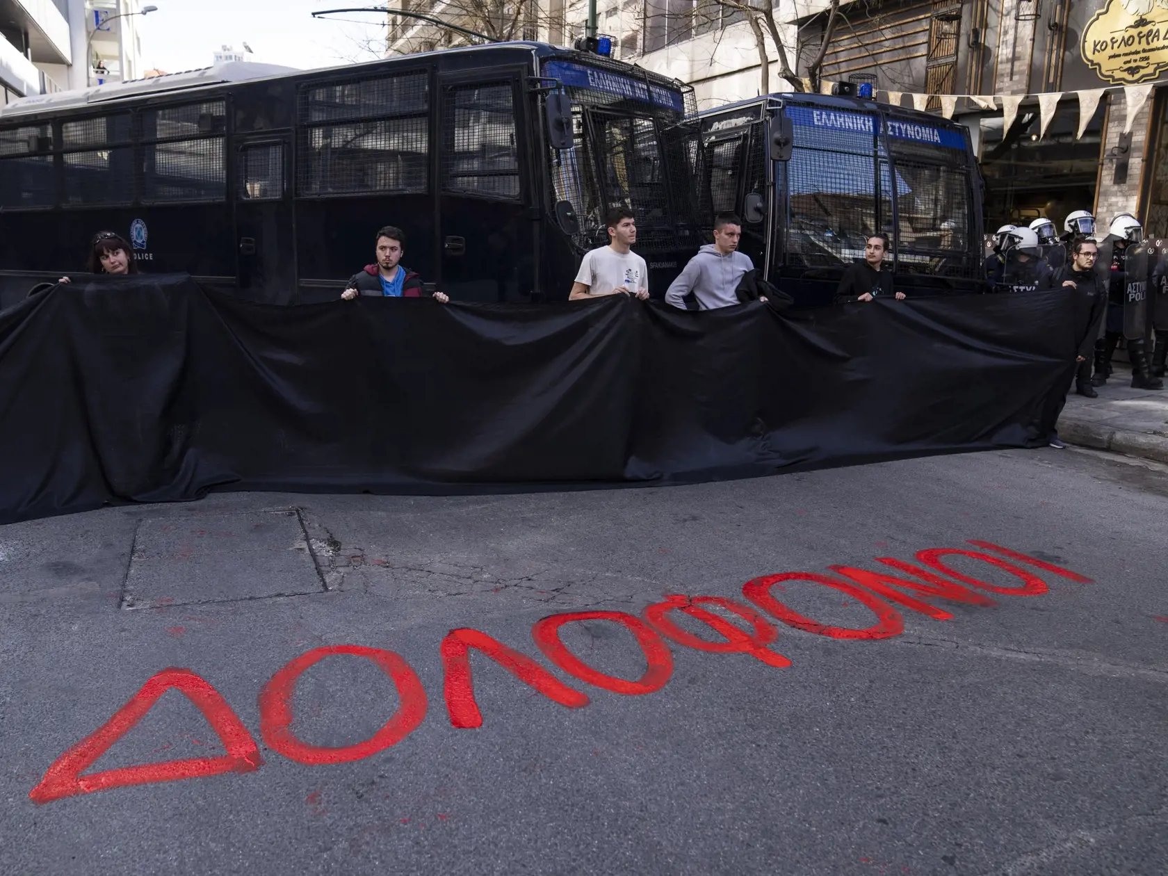 JB 11 Atény - Univerzitní študenti držia čierny transparent pred namaľovaným červeným nápisom na ulici počas protestného zhromaždenia pred sídlom železničnej spoločnosti Hellenic Train v Aténach 3. marca 2023. Stovky protestujúcich si pred gréckym parlamentom v piatok minútou ticha uctili pamiatku obetí utorkovej tragickej čelnej zrážky dvoch vlakov, informuje agentúra AFP, od ktorej TASR správu prevzala. Pred budovou gréckeho parlamentu protestovali najmä študenti v rámci série demonštrácii nap