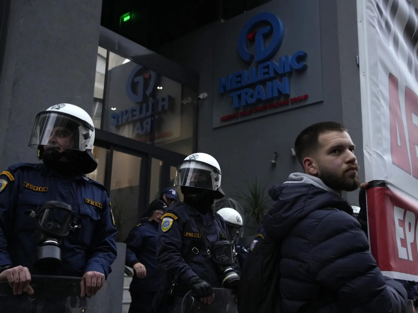 JB 30 Atény - Demonštrant drží transparent pred príslušníkmi poriadkových síl, ktorí hliadkujú pred sídlom železničnej spoločnosti Hellenic Train počas protestu v Aténach 2. marca 2023. Približne 700 ľudí sa vo štvrtok zhromaždilo pred sídlom železničnej spoločnosti Hellenic Train v Aténach, kde protestovali proti chronickým nedostatkom a zlyhaniam. Tie v utorok krátko pred polnocou spôsobili čelnú zrážku dvoch vlakov s 57 mŕtvymi. TASR prevzala správu z tlačovej agentúry AFP.    Protestujúci si