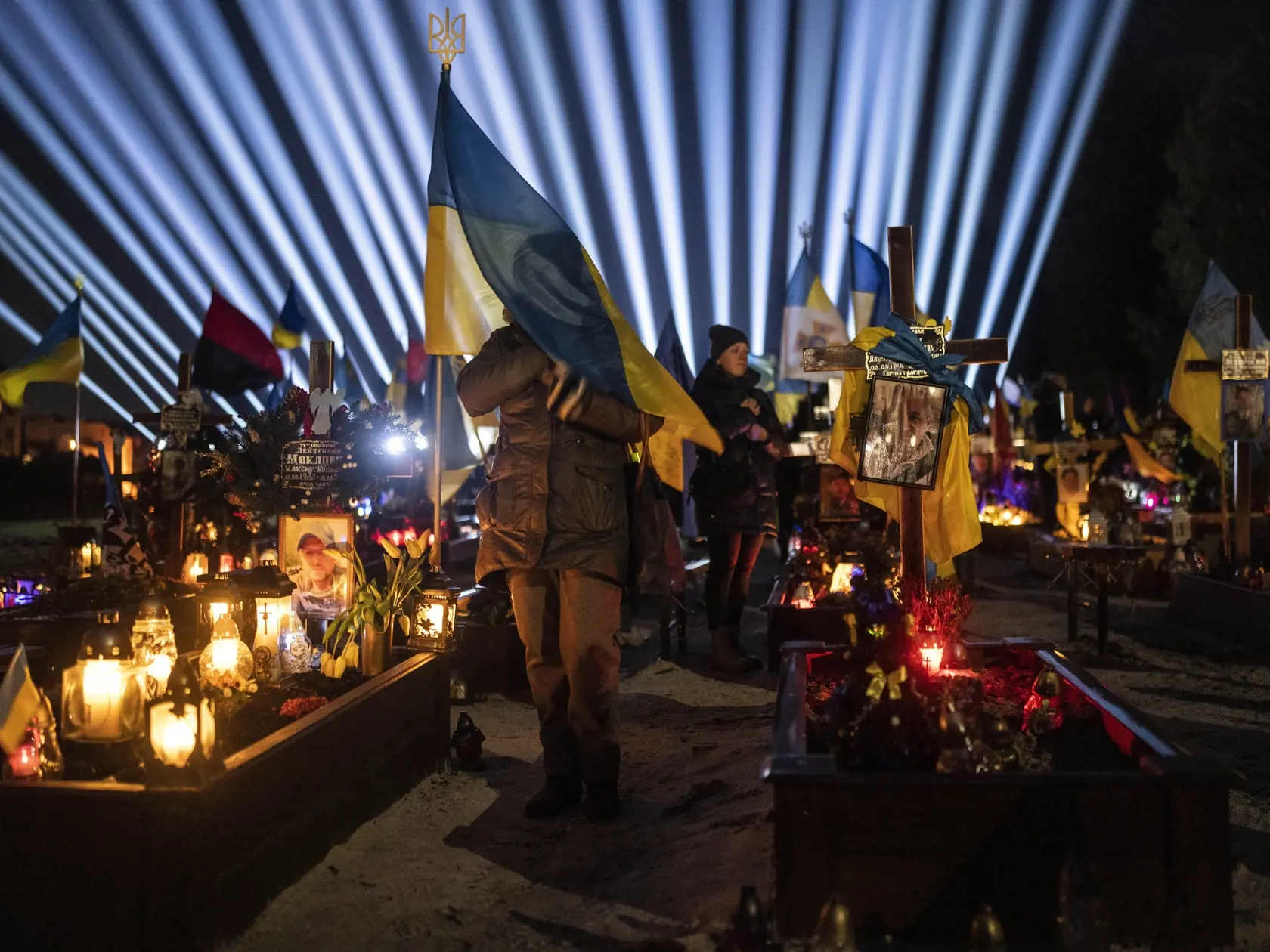 Na snímke žena počúva ukrajinskú národnú hymnu na cintoríne v Ľvove vo štvrtok 23. februára 2023. Rodinní príslušníci sa zišli na vojenskom cintoríne v Ľvove, aby si uctili pamiatku tých, ktorí zahynuli v boji proti ruskej invázii na Ukrajine.